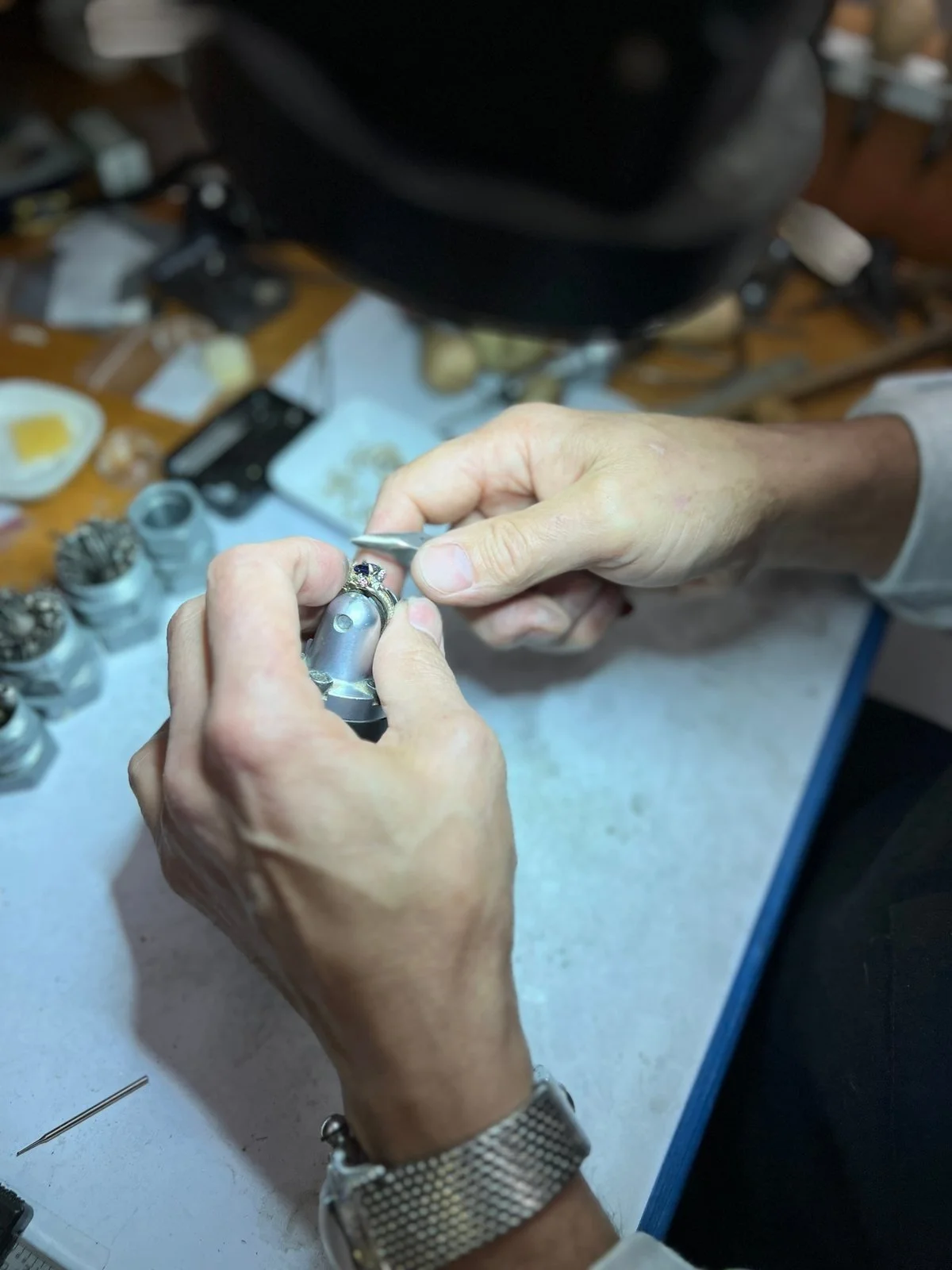 Rebuilding the prongs on a three-stone emerald and diamond ring: the emerald is removed, new gold prongs are fitted, then the stone is reset securely.