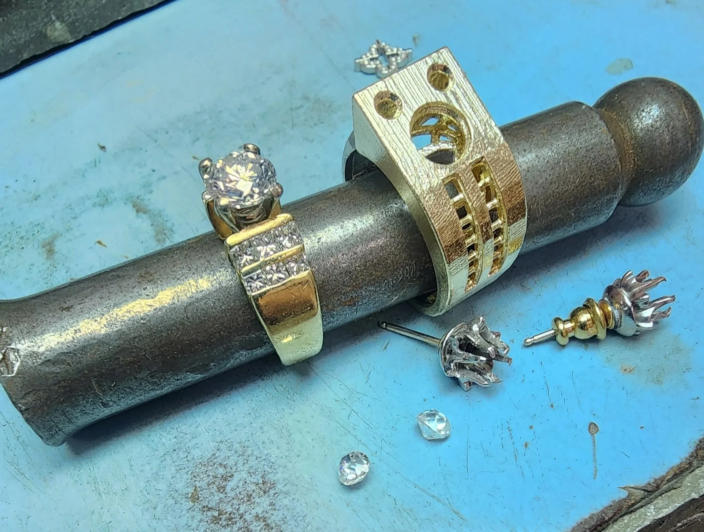 Original diamond ring beside its redesigned yellow gold setting on a ring mandrel at Kaz Jewelry in Laguna Niguel.