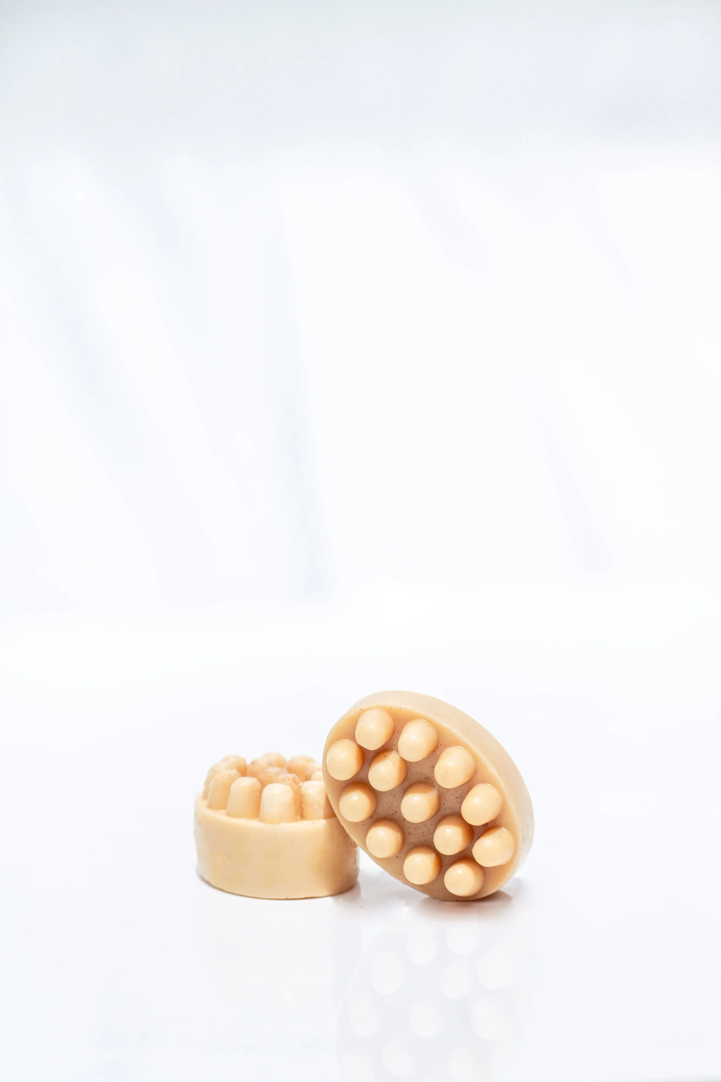 Two orange turmeric colored soap bars and textured surface, placed on a white background.