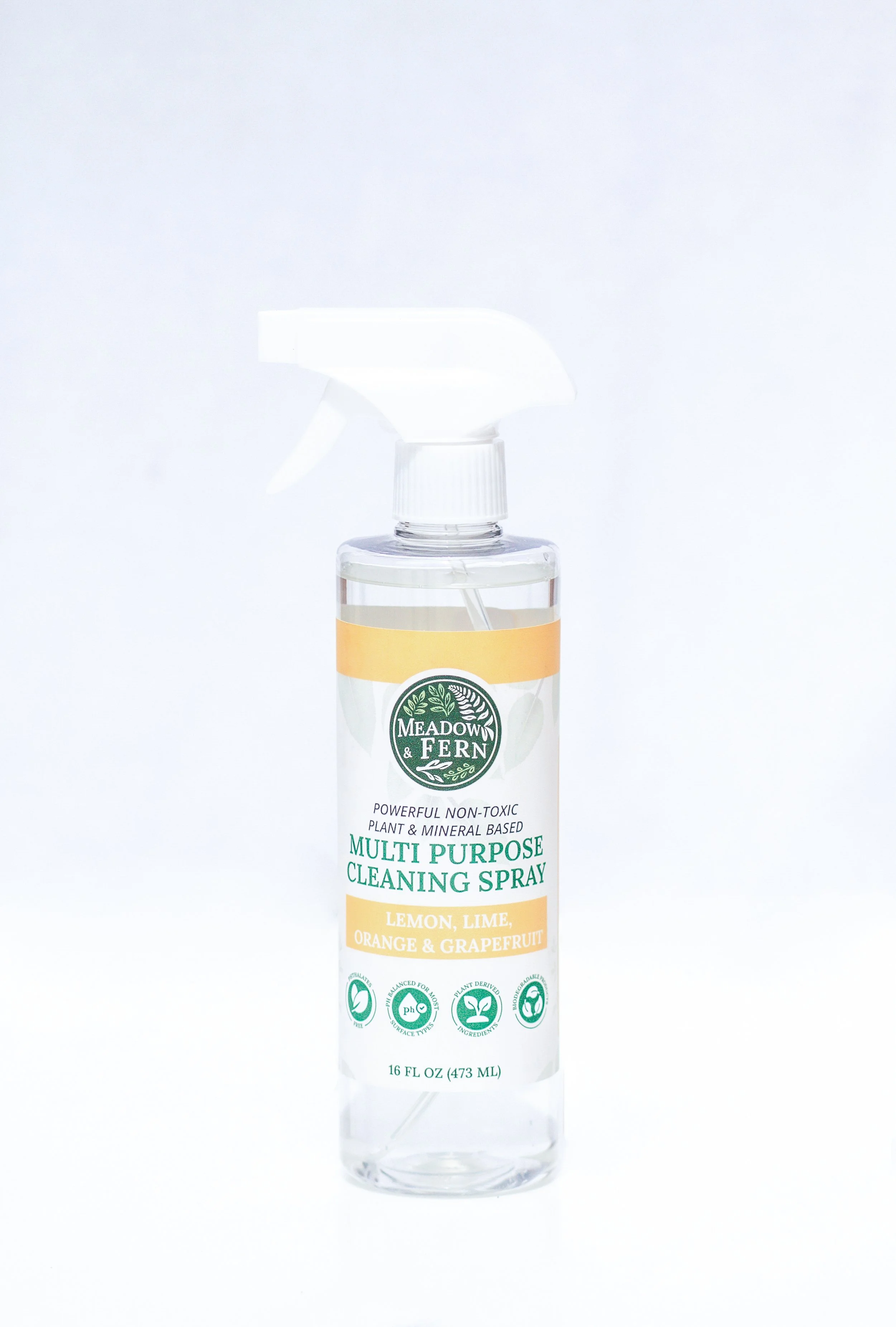 A clear spray bottle of Meadow & Fern multi-purpose cleaning spray with a white spray nozzle, label indicating lemon, lime, orange, and grapefruit scent, and 16 ounces capacity.