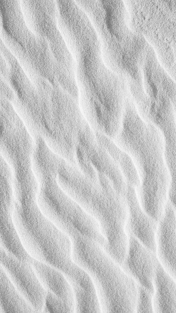 Close-up of white sandy beach with rippled texture.
