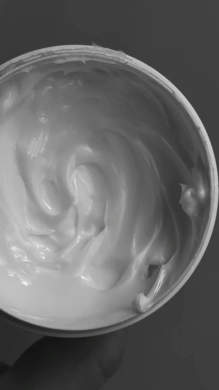 A black and white photo of a container filled with a creamy, swirled substance, possibly yogurt or whipped cream.