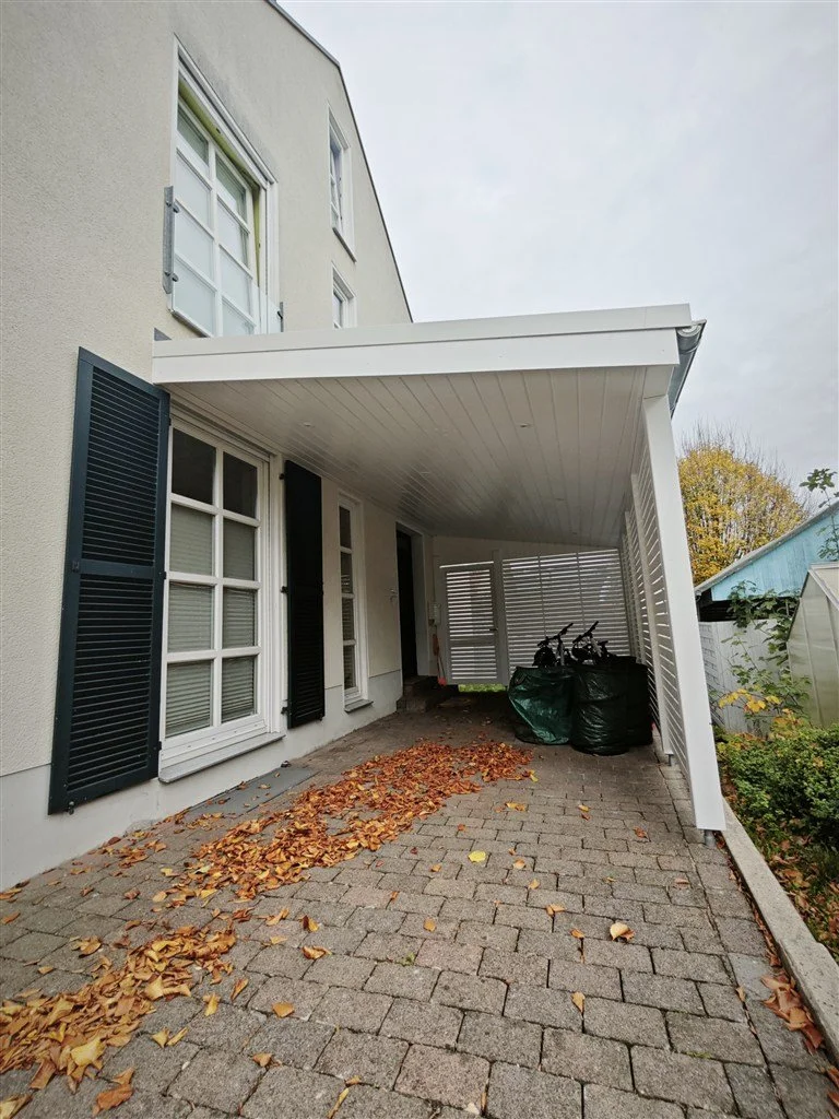 Unbehandeltes Holz-Carport in Weiß, mit eleganter Fichte Rhombusprofil-Verkleidung, direkt am Haus als Haustürüberdachung montiert.
