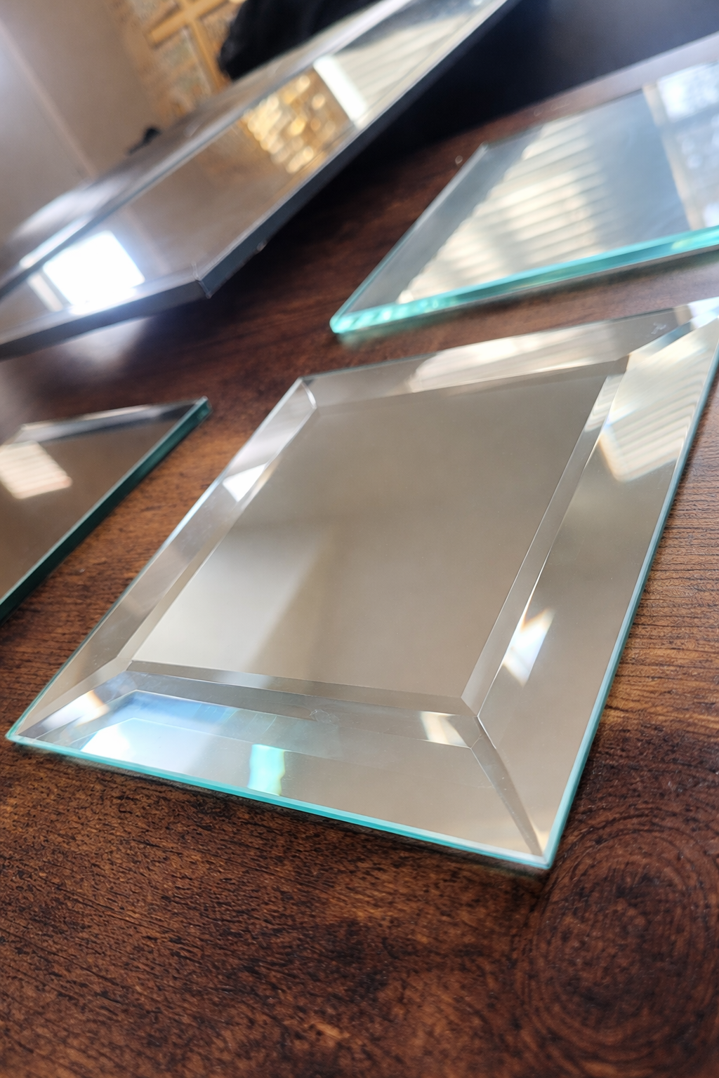 Close-up of empty glass serving trays on a wooden table, with reflections and natural light