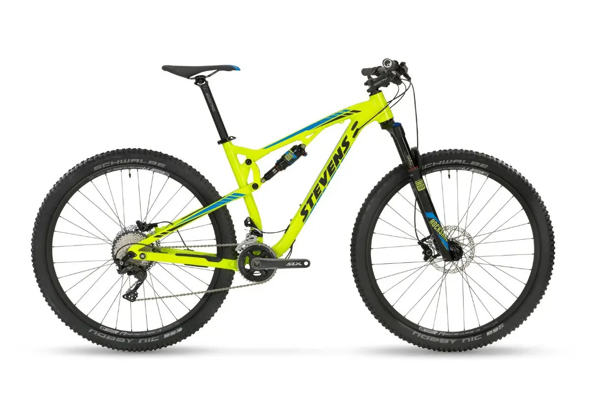 Una bicicleta de montaña amarilla con detalles en negro y azul y neumáticos anchos, sobre fondo blanco.