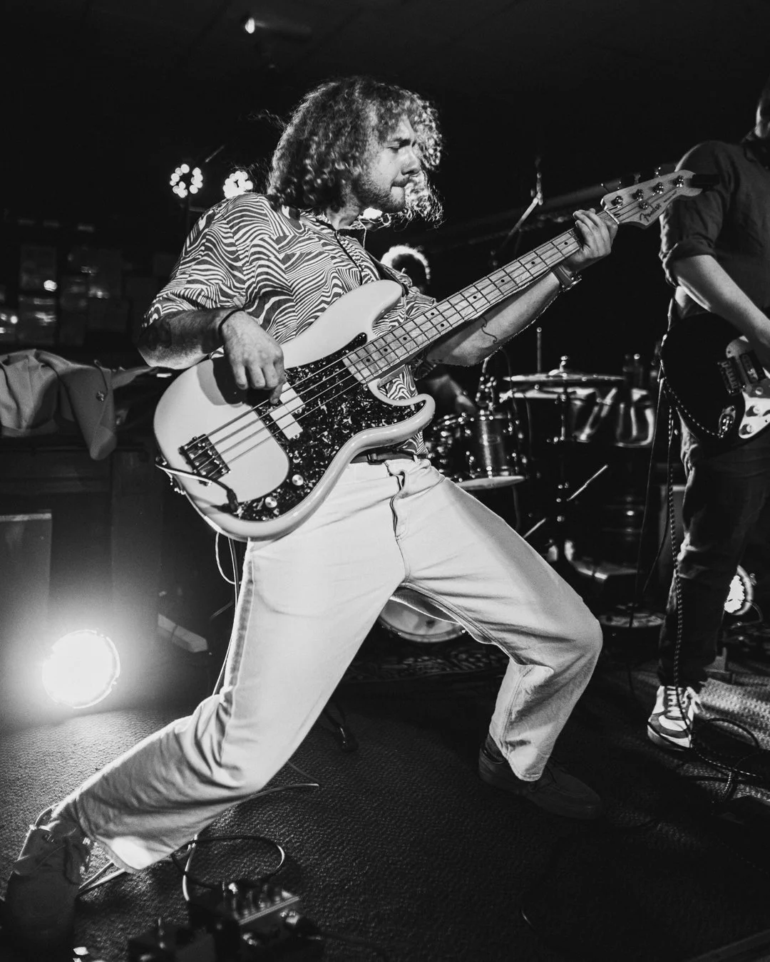 A musician playing an electric bass guitar on stage during a live performance.