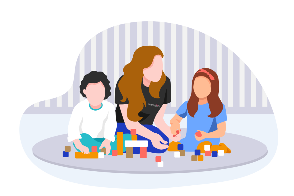 A woman with long red hair and two young girls with brown hair playing with colorful building blocks on a round rug in a room with light gray striped walls.