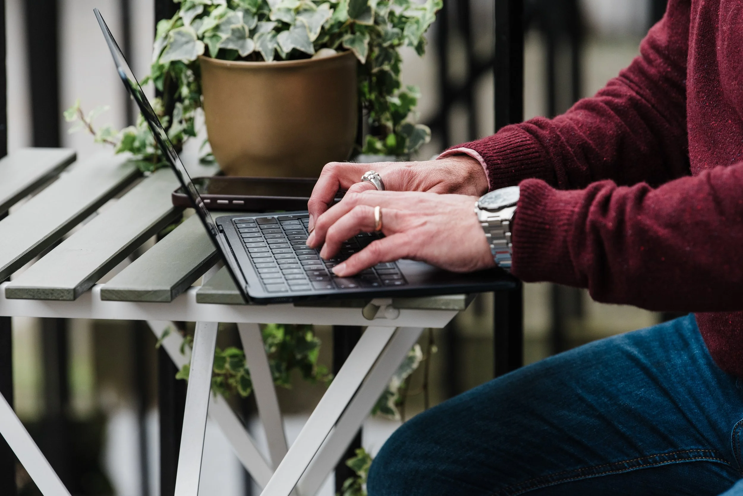 JR McCoy writing a blog on a laptop outdoors, sharing thoughts and inspiration behind Wolsey's Adventures.