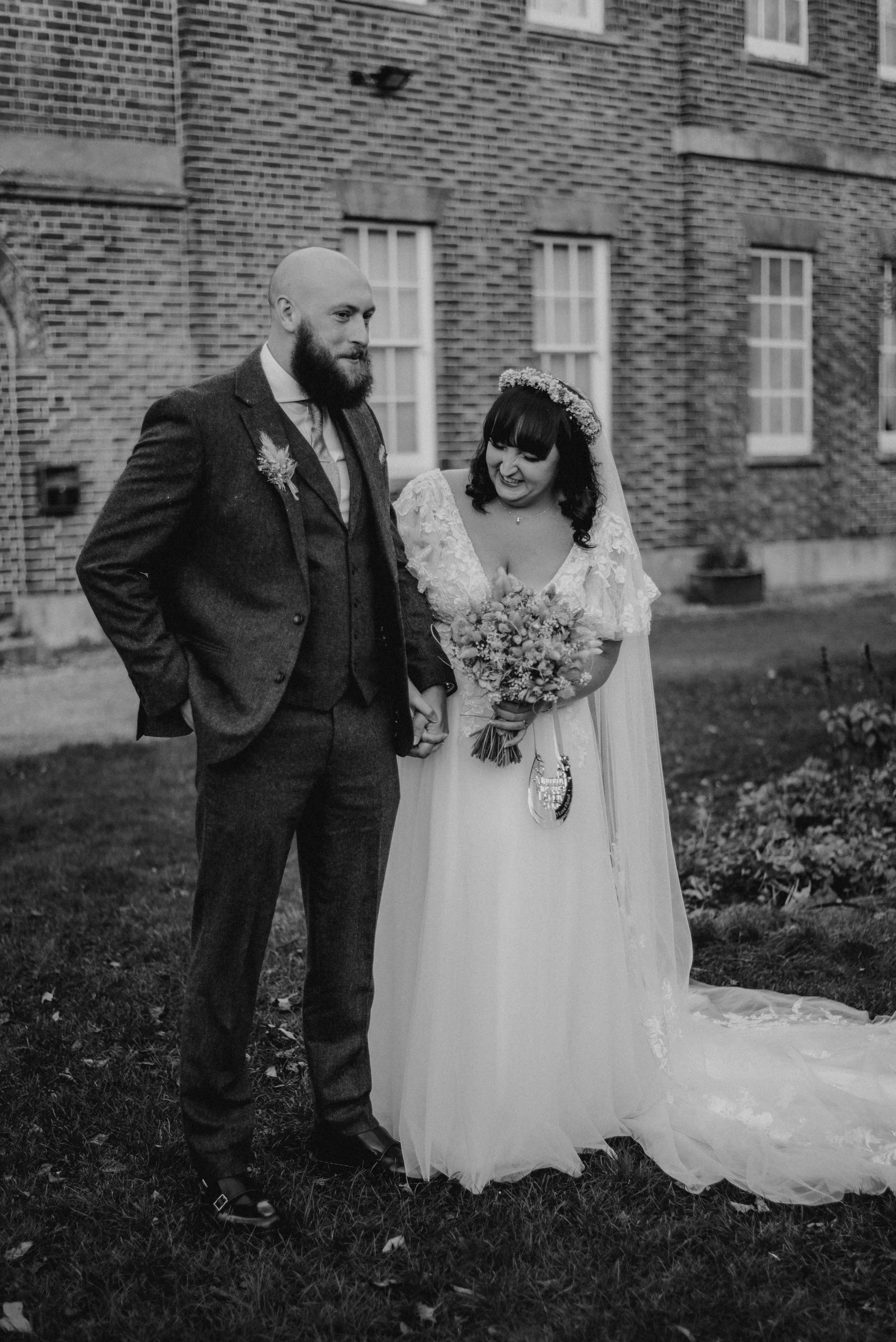A young woman with curly hair and glasses smiling in a brightly lit room.