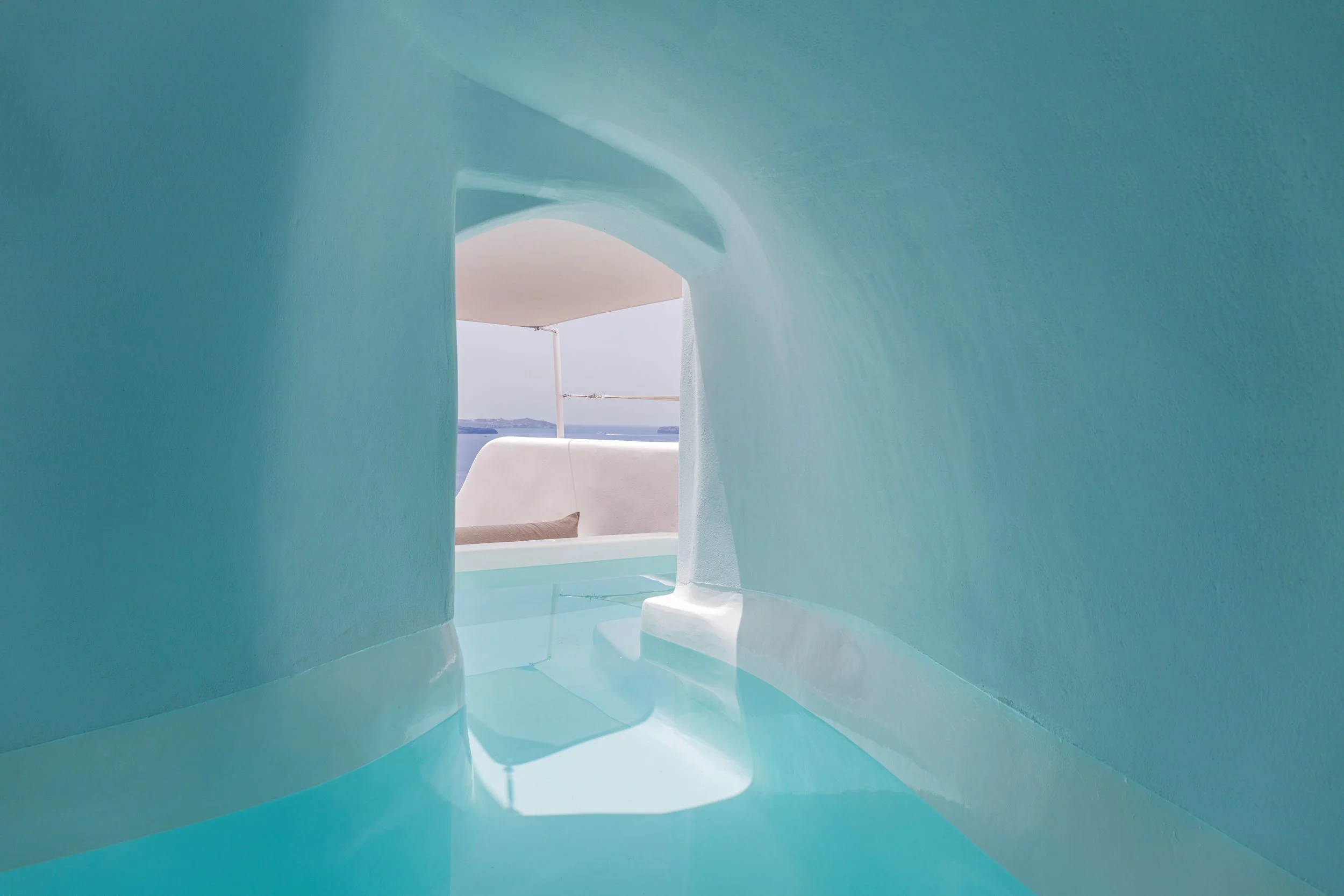 view of the ocean through an opening in a white and blue structure, with a curved ceiling and reflective floor.