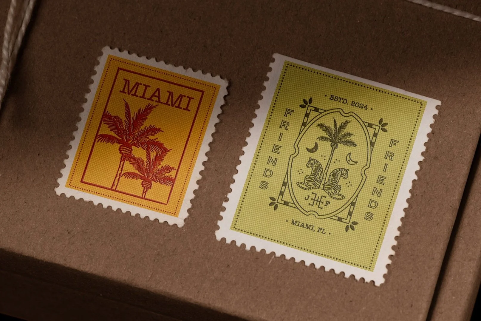 Two decorative stamps on a brown surface. The left stamp is yellow with "Miami" and palm trees. The right stamp is green with "FRIENDS", two tigers, a palm tree, and "MIAMI, FL".