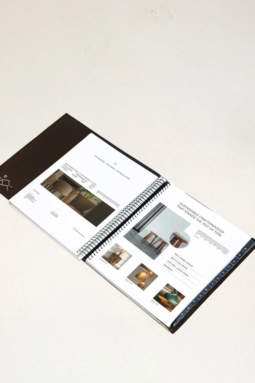 Open spiral-bound brochure on a flat surface displaying furniture images and descriptions, focused on sustainable craftsmanship.