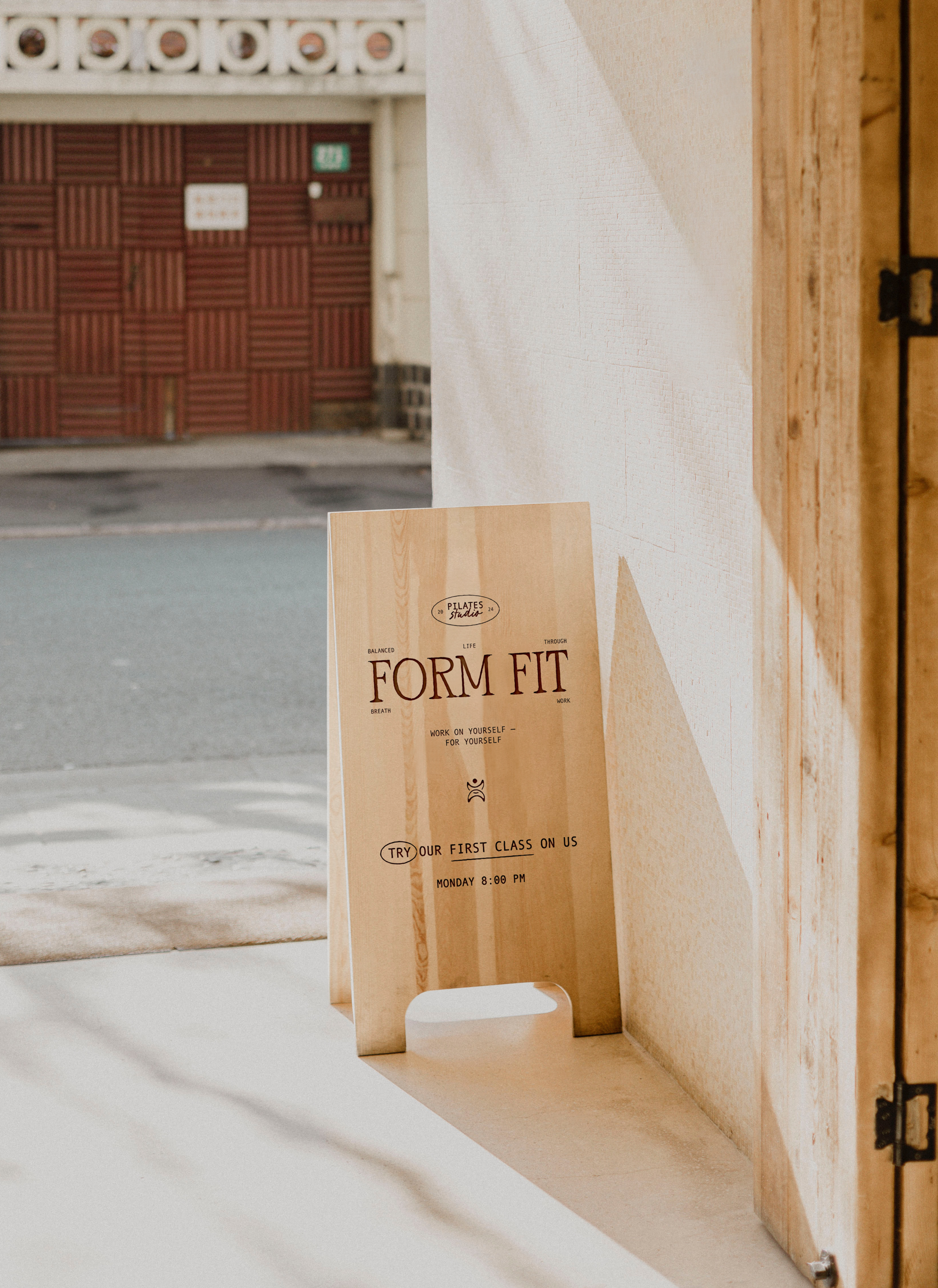 Wooden sandwich board promoting "Form Fit" Pilates studio with offer for a free first class.