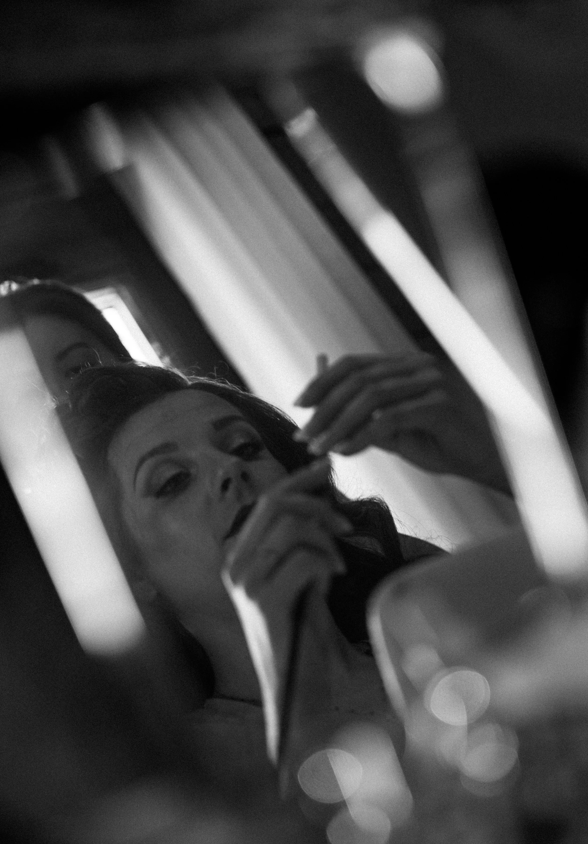 Une femme se regarde dans un miroir, prenant une selfie avec un téléphone, dans un environnement sombre.