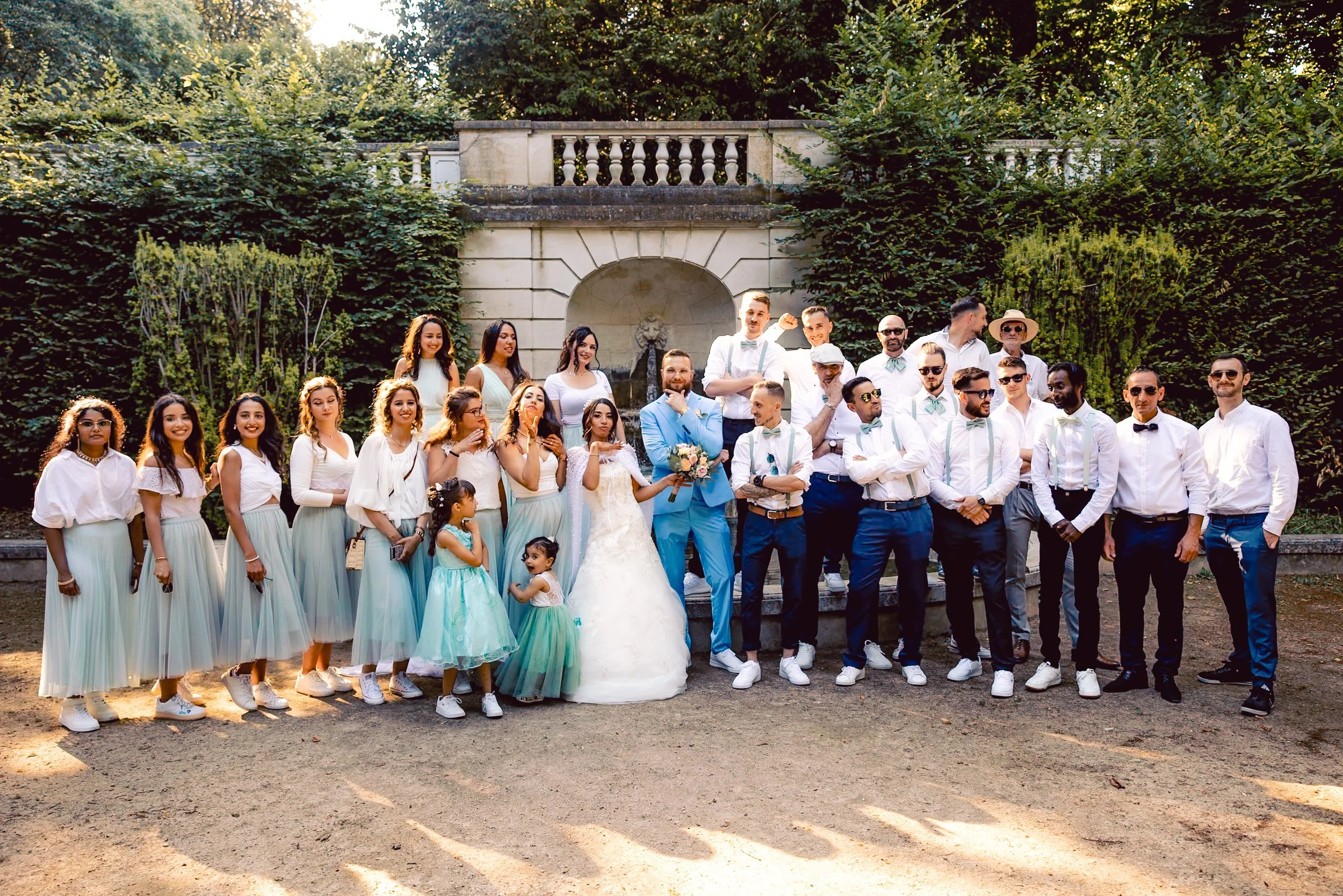 Groupe de personnes lors d'un mariage, avec le couple de mariés au centre, entouré d'invités en tenue formelle dans un jardin