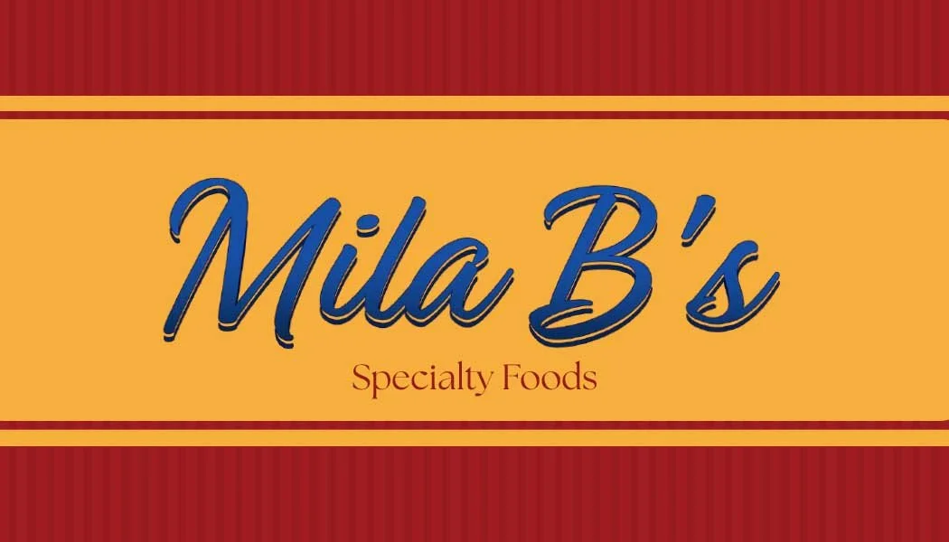 Sign for Mila B's Specialty Foods with red and yellow background and blue text.