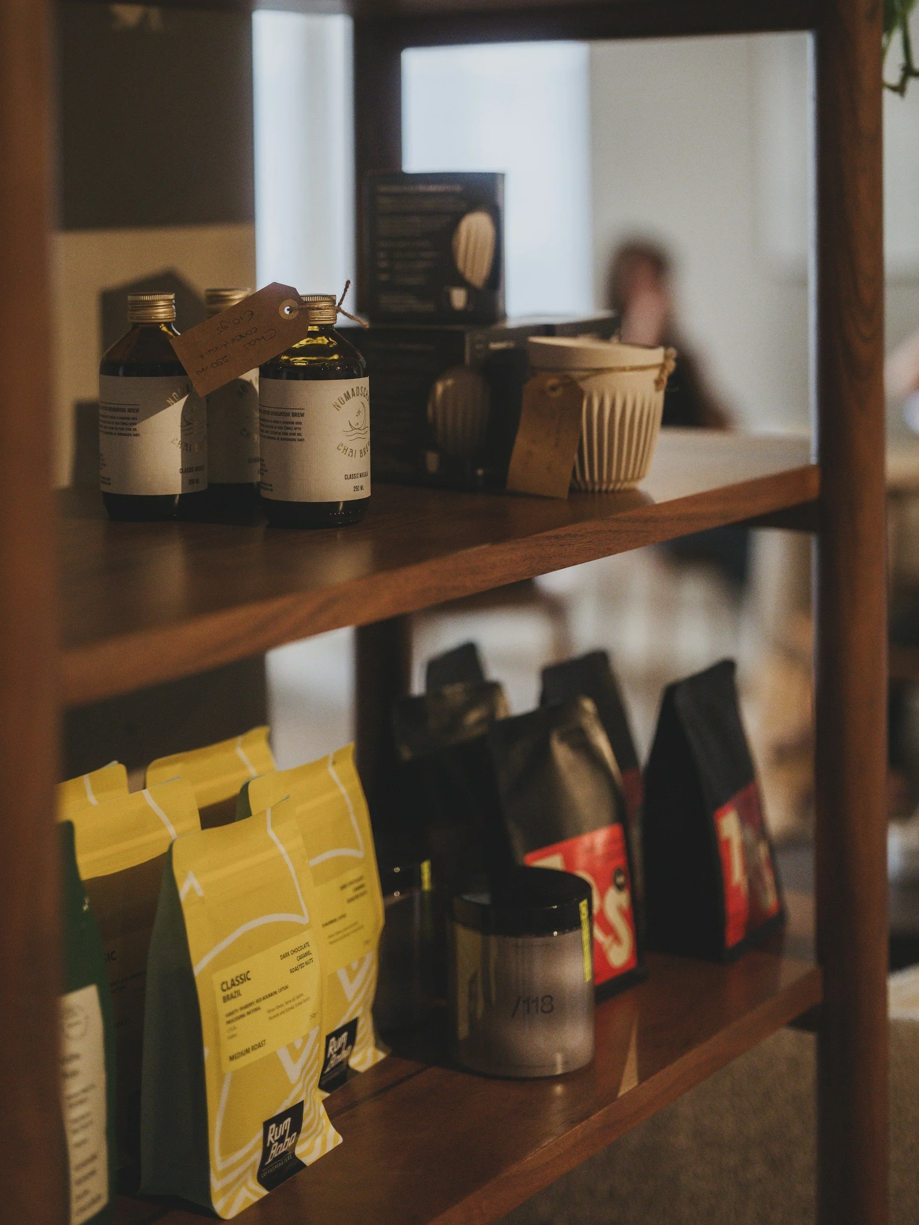 Shelf displaying bags of coffee beans and coffee brewing accessories in a shop.