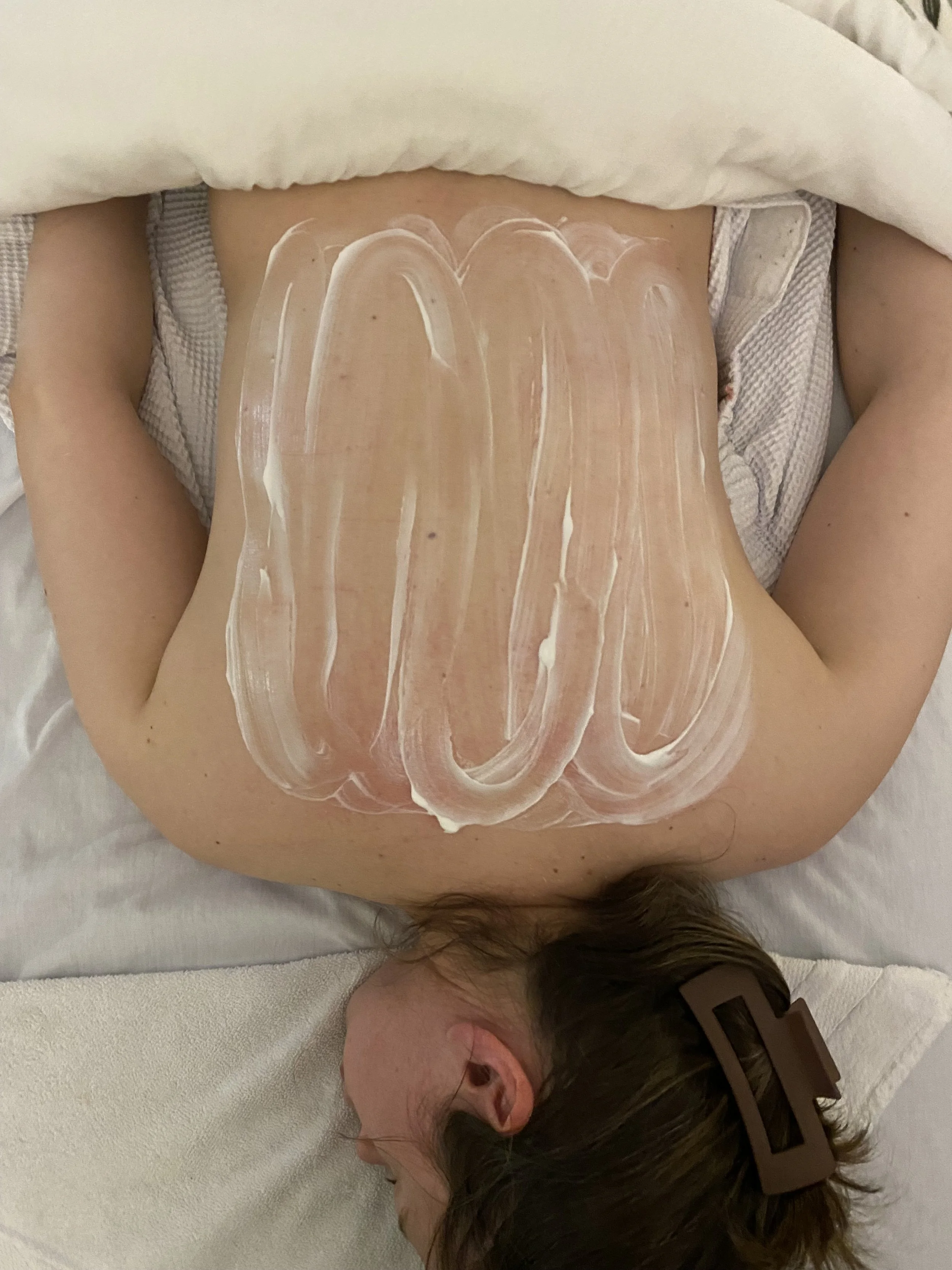 customer laying face down on spa bed with mask on her back