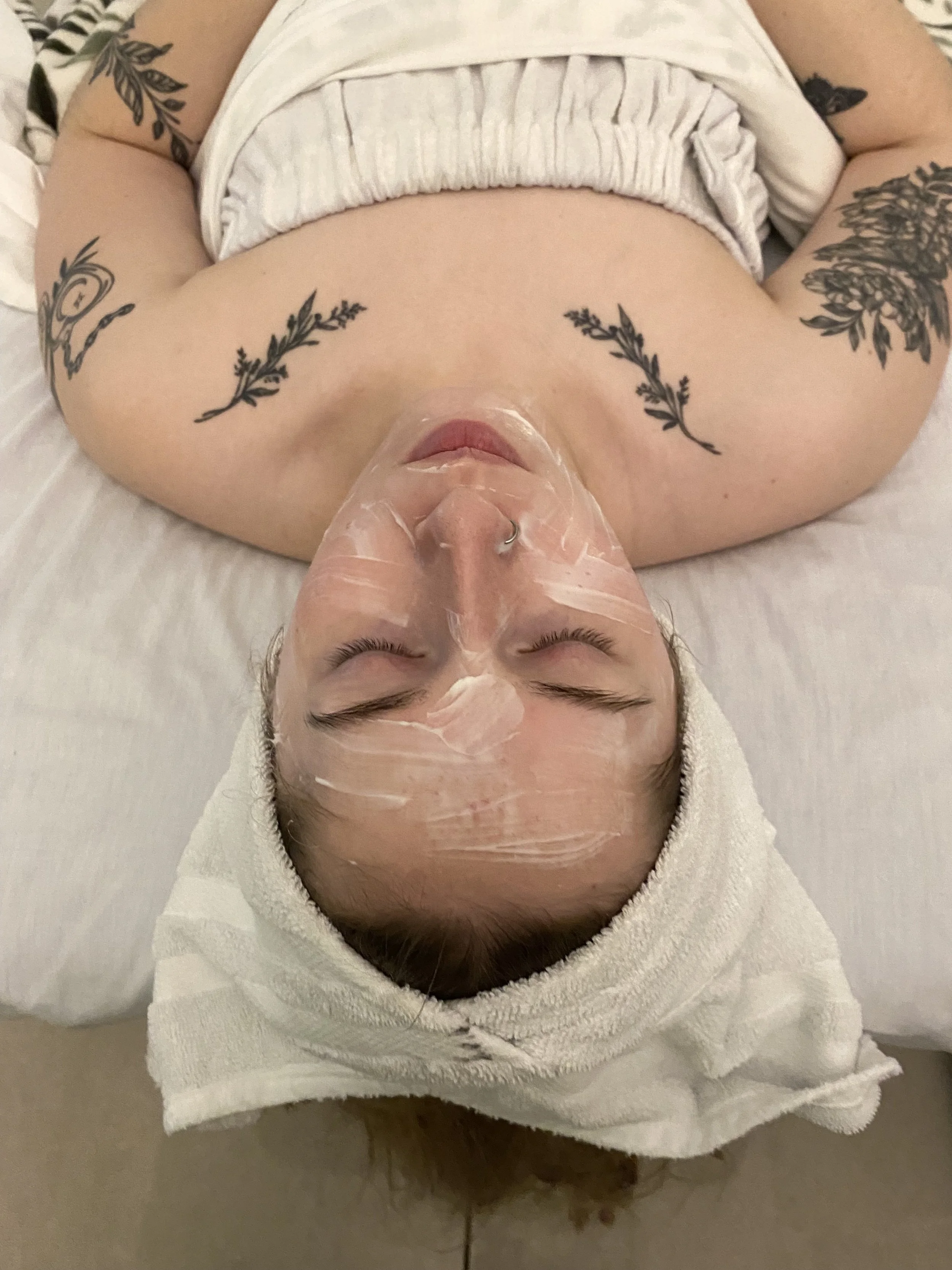 client laying in spa bed with towel on, resting with a face mask on