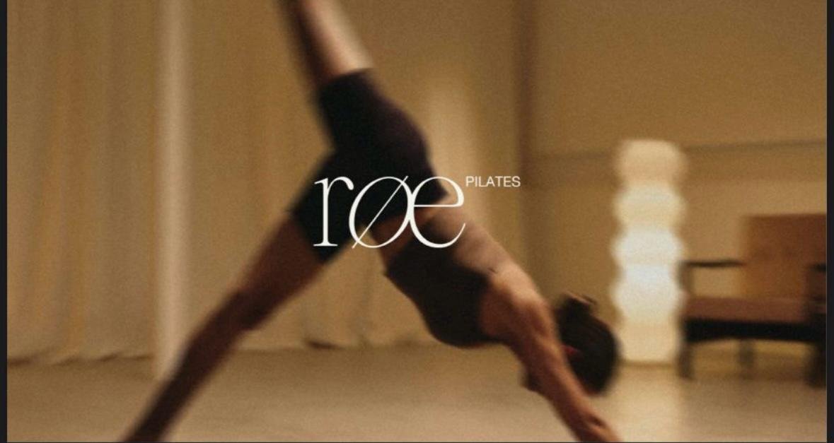 A person performing a yoga pose in a dance or exercise studio, with the logo 'roe PILATES' overlaid.