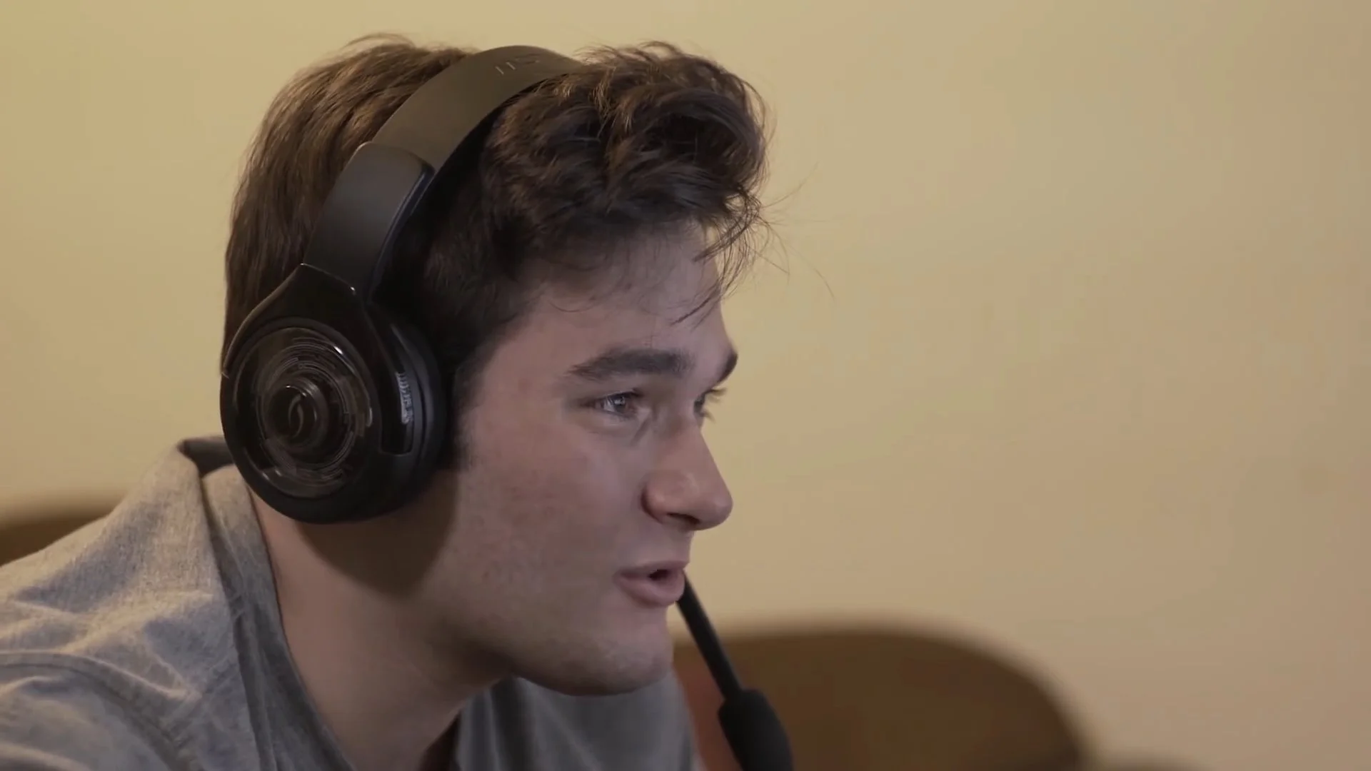 Young man wearing a headset with a microphone, looking intently at something, side profile view.