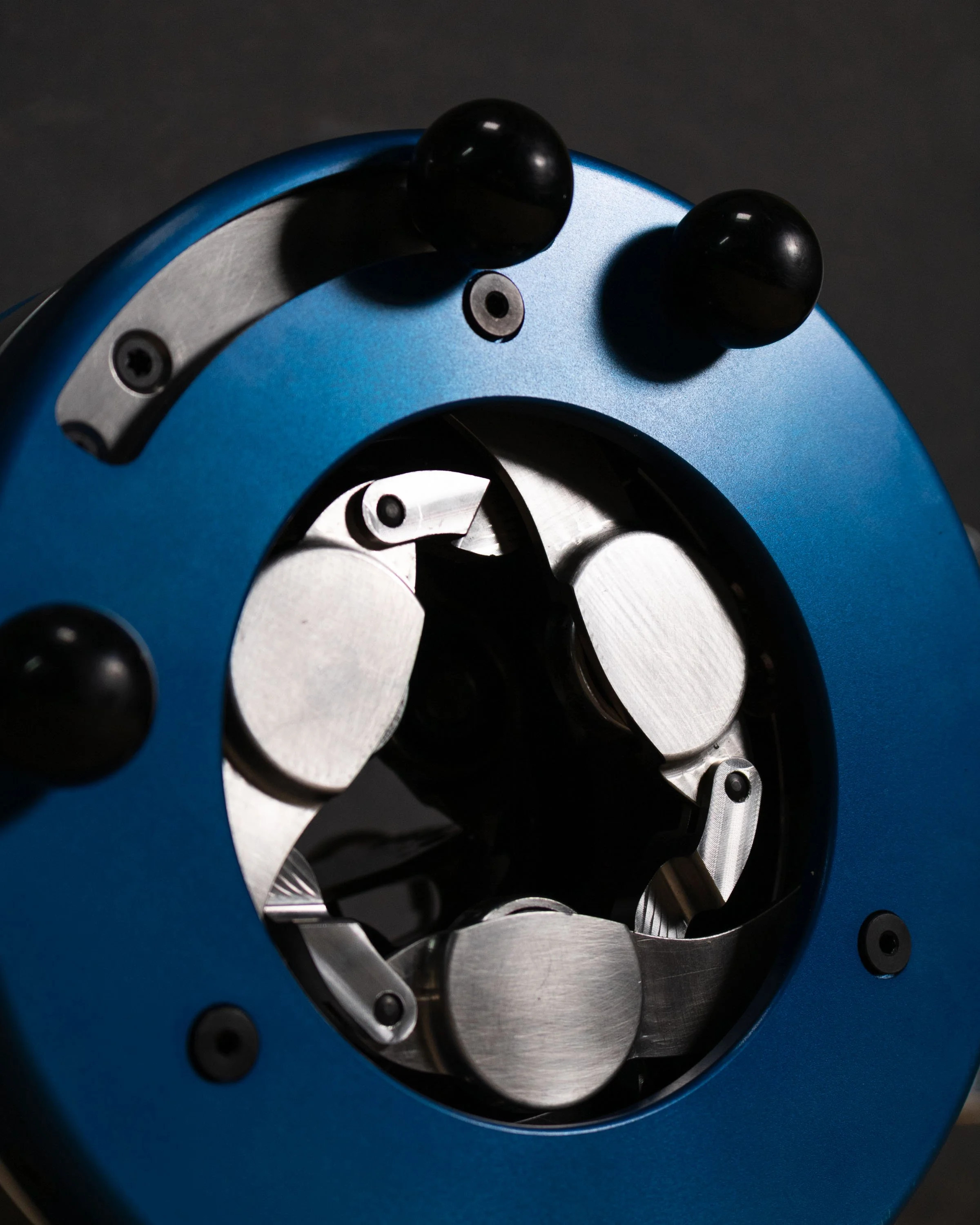 Close-up of a blue mechanical device with black knobs and visible metallic internal gears.