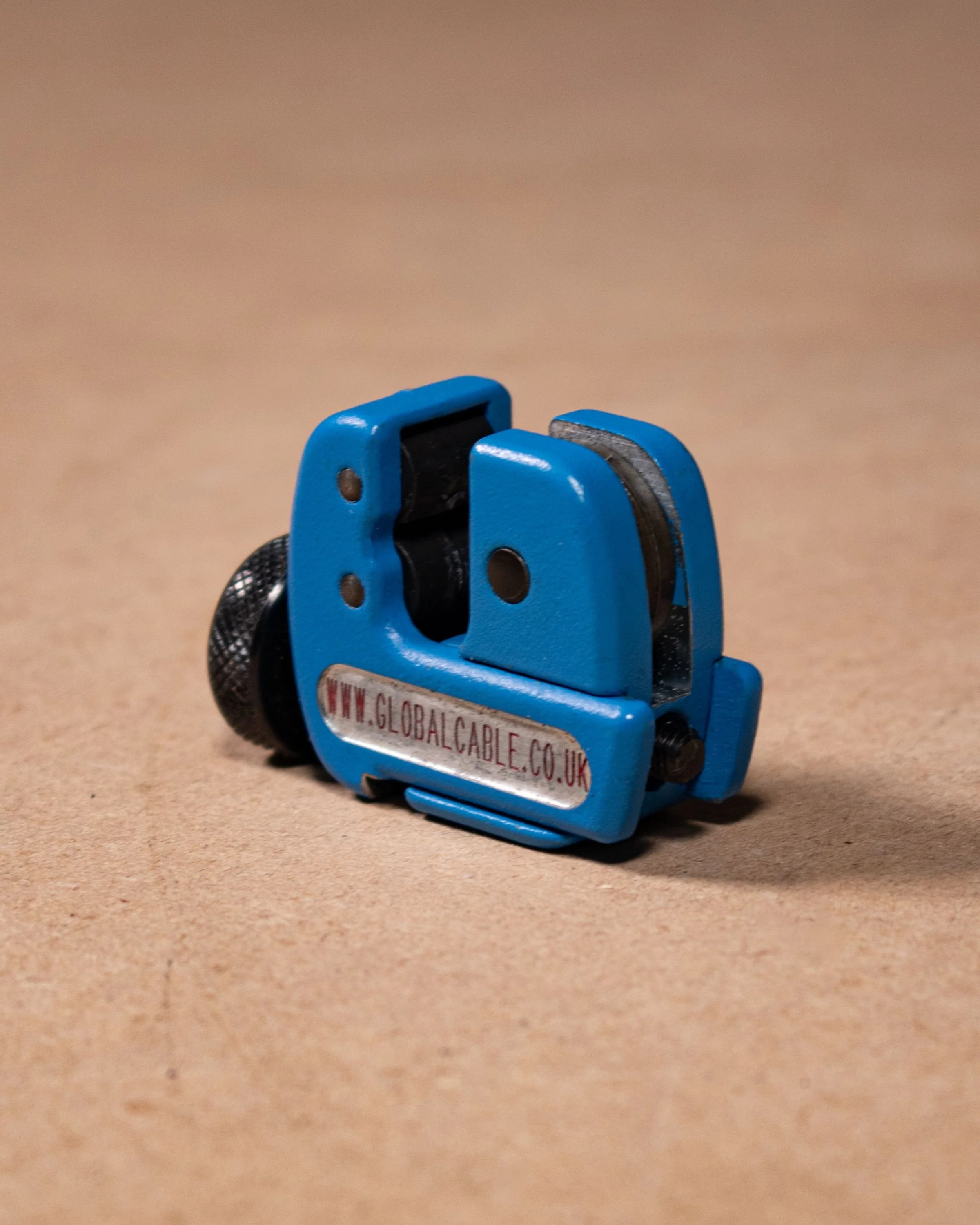 A blue cable puller tool with black and silver components on a brown surface, with a web address sticker reading 'www.globalcable.co.uk'.