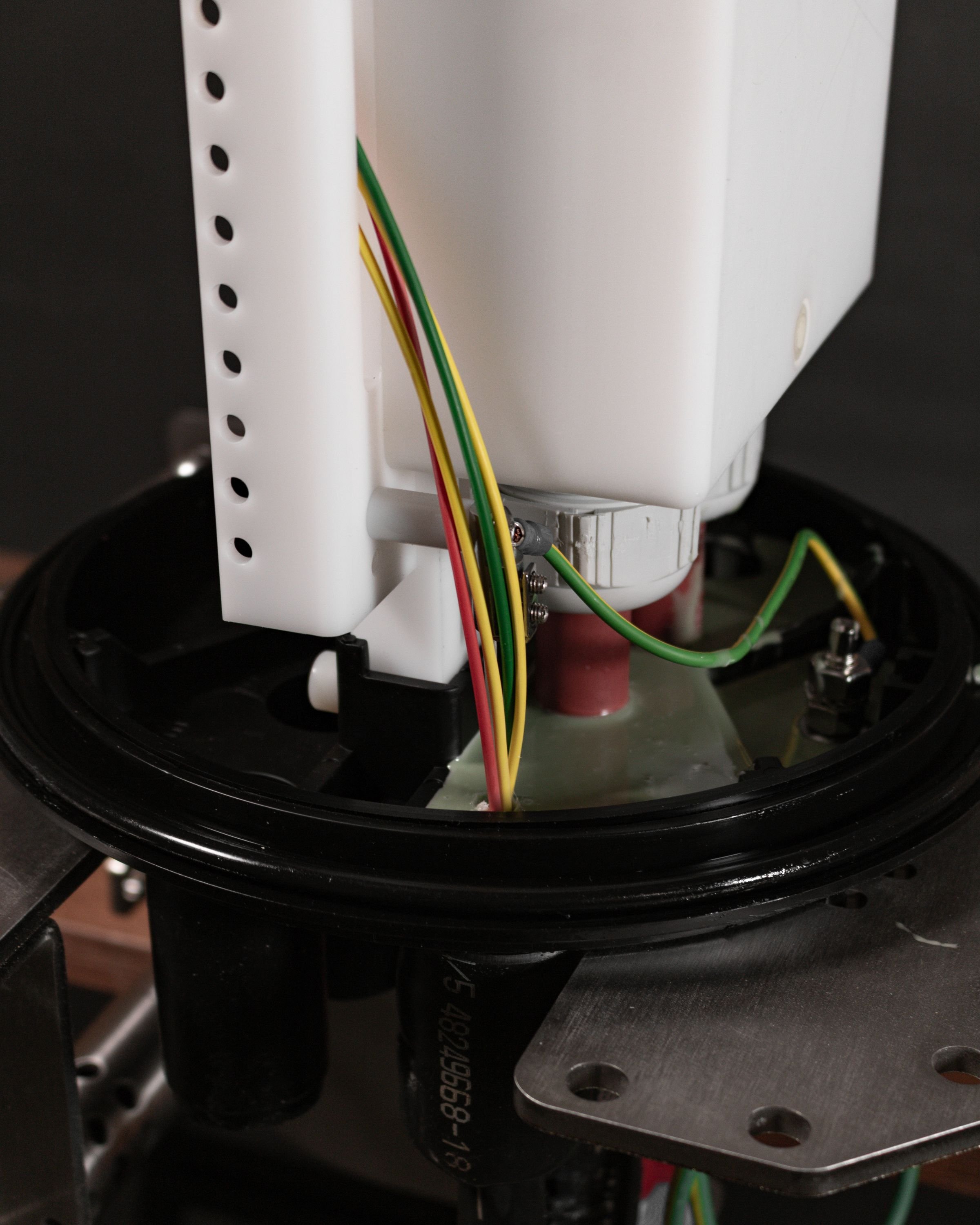 Close-up of the internal components of a Universal Land Joint, showing a white plastic structure with fibre wires connected to various parts, and a black circular base.
