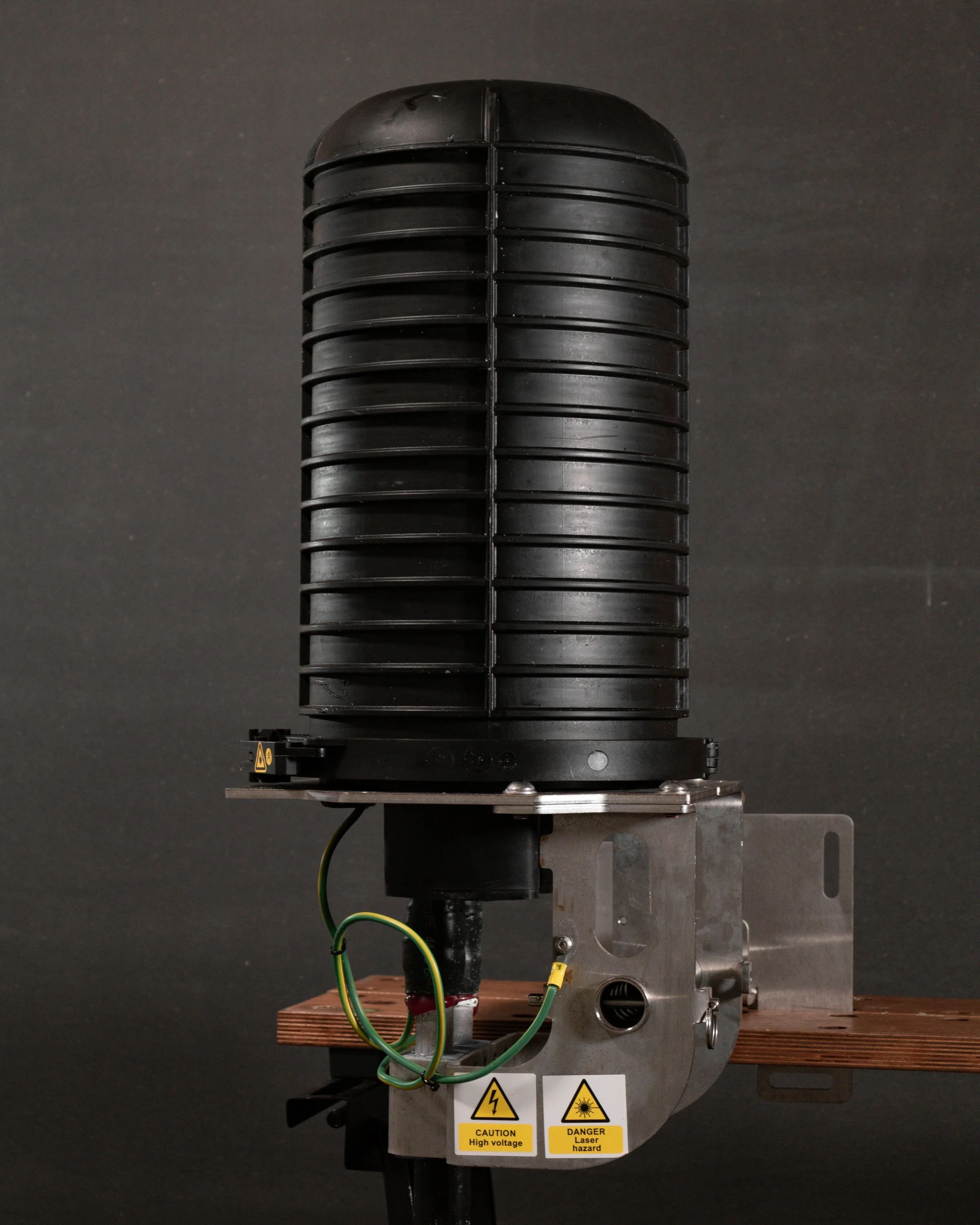 A Global Cable Universal Land Joint with warning labels, mounted on a table against a dark background.
