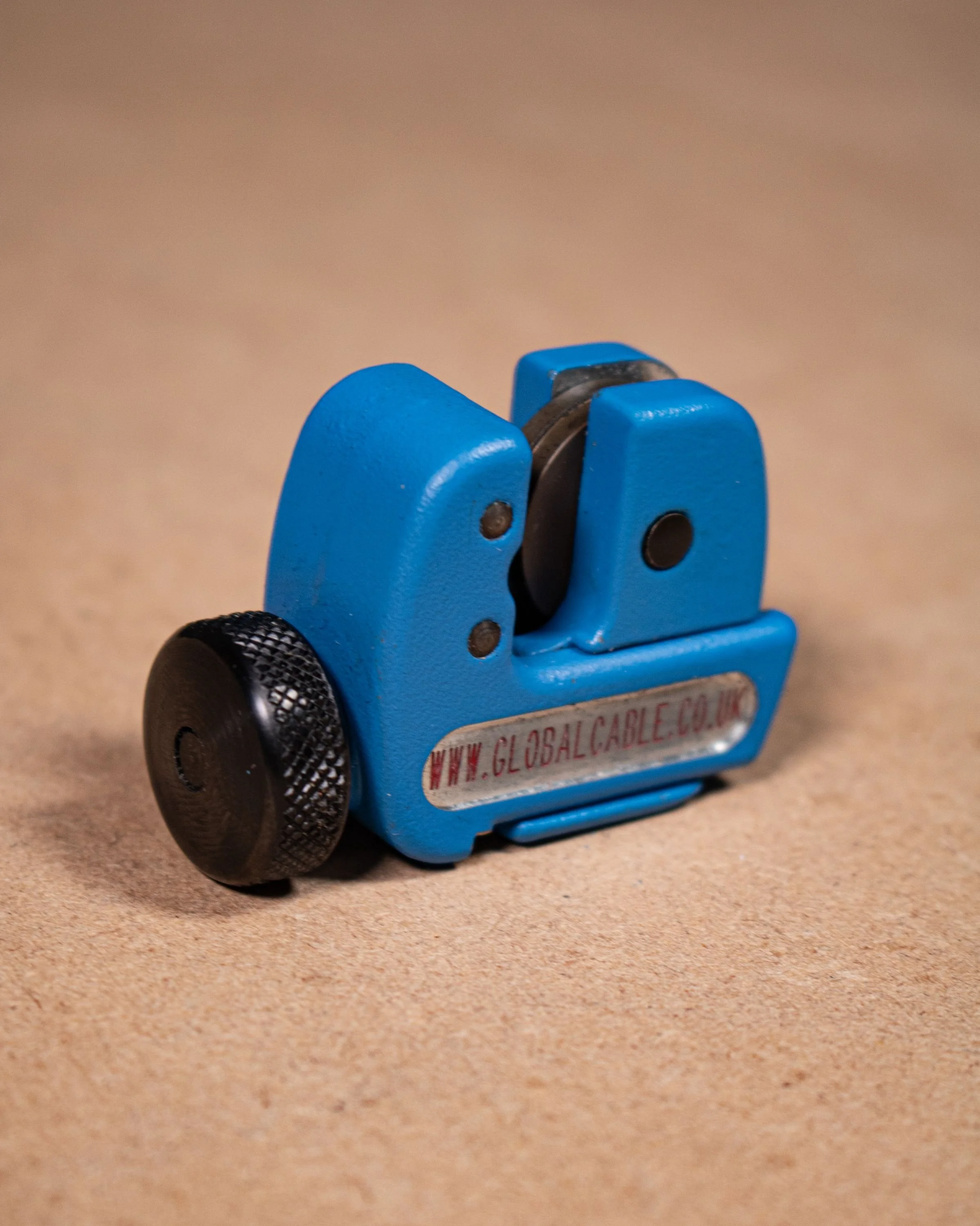 Small blue cable reel with black knob on a brown surface.