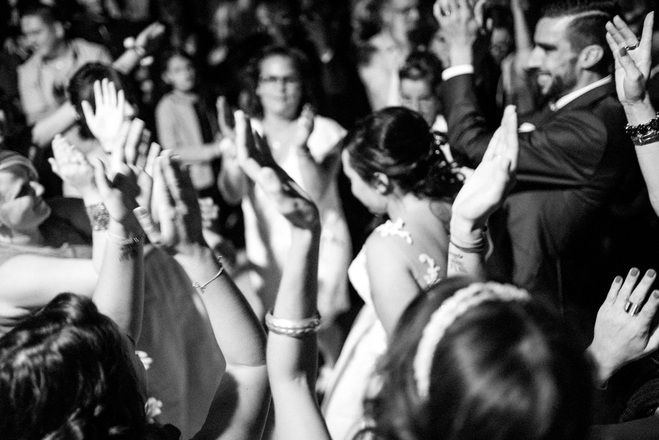 Group of people dancing and celebrating, with some raising their hands, at a lively event or party.