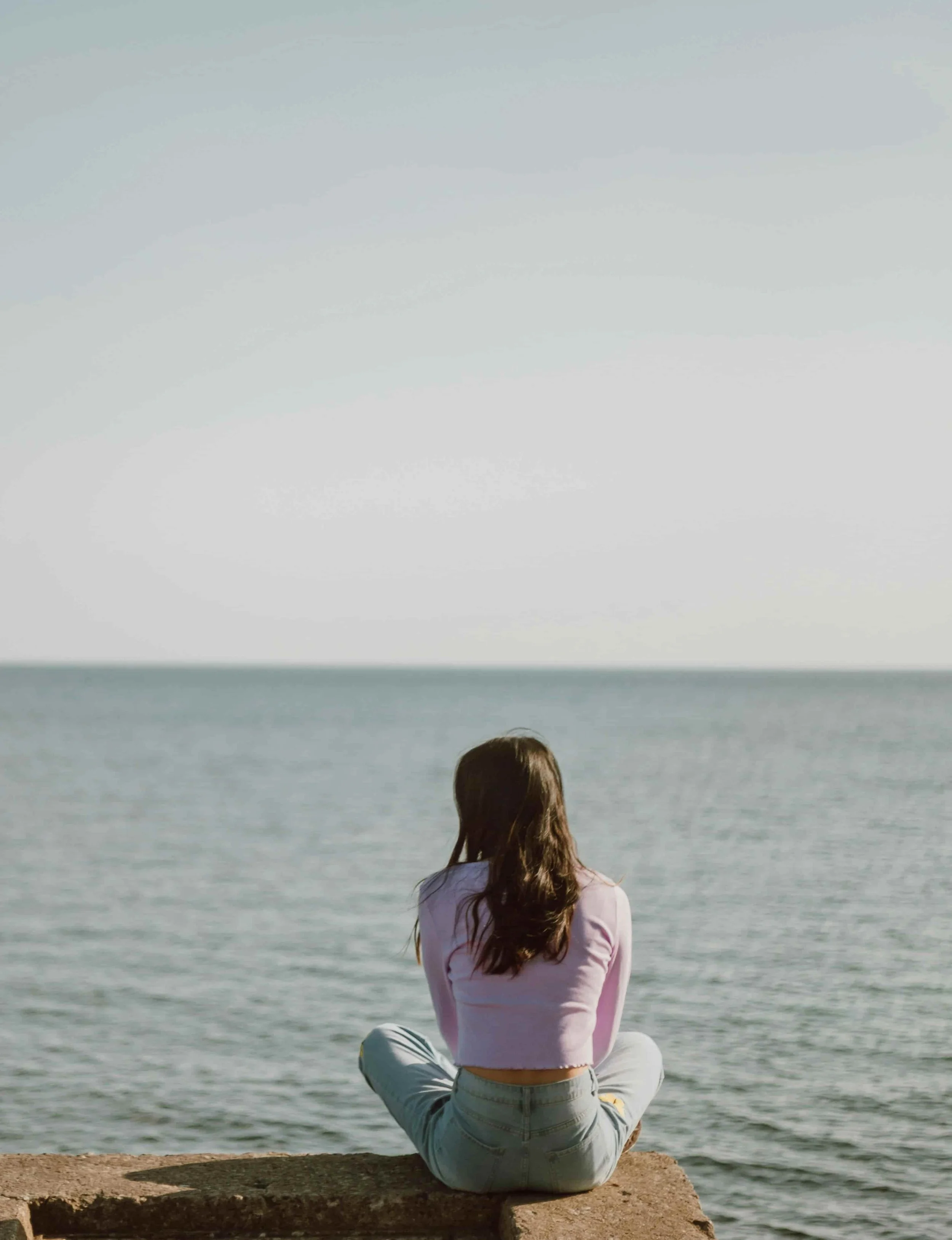 Asian American woman learning to stop being a people pleaser while she is sitting by the water