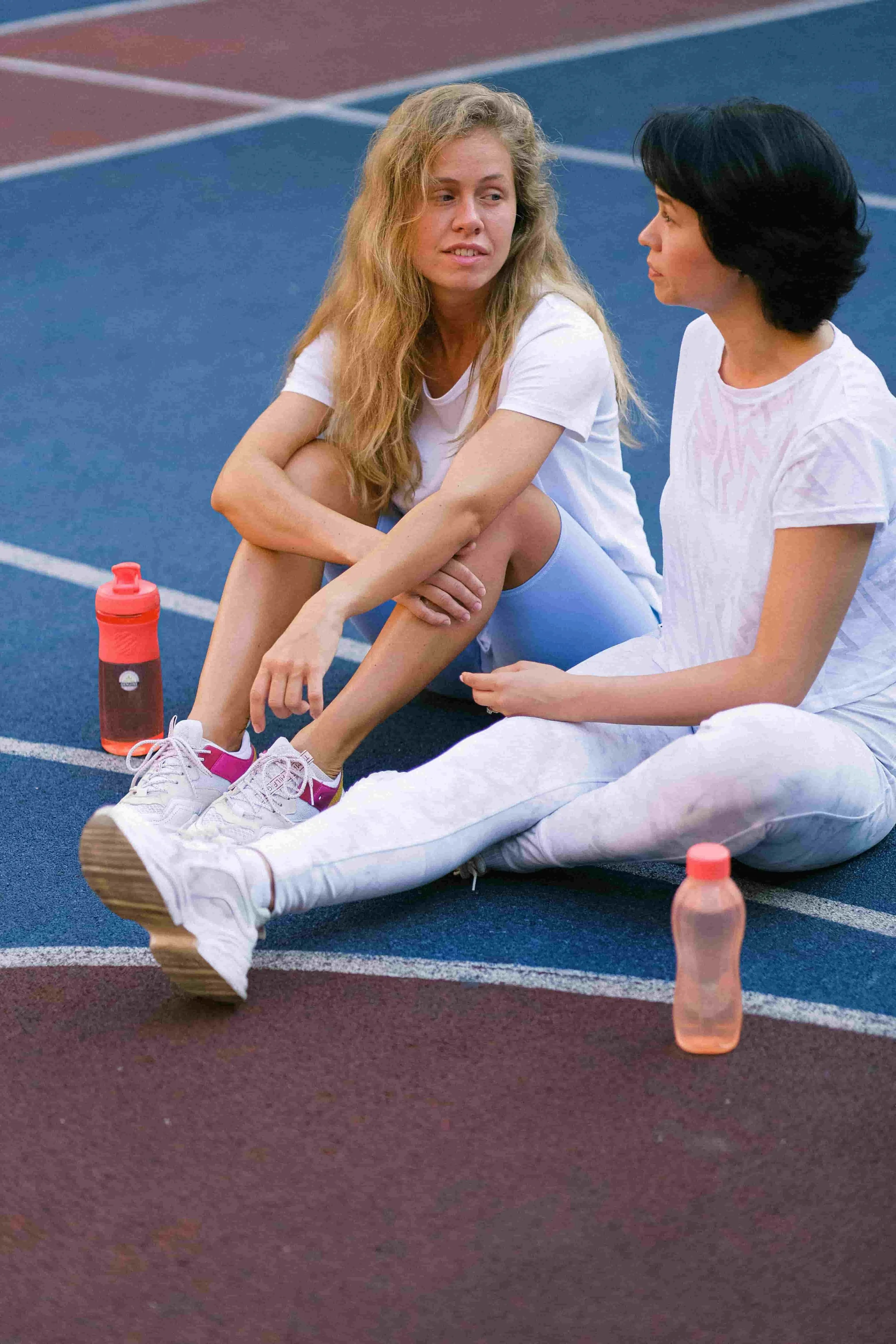 Two runners talking while sitting on the track after a workout
