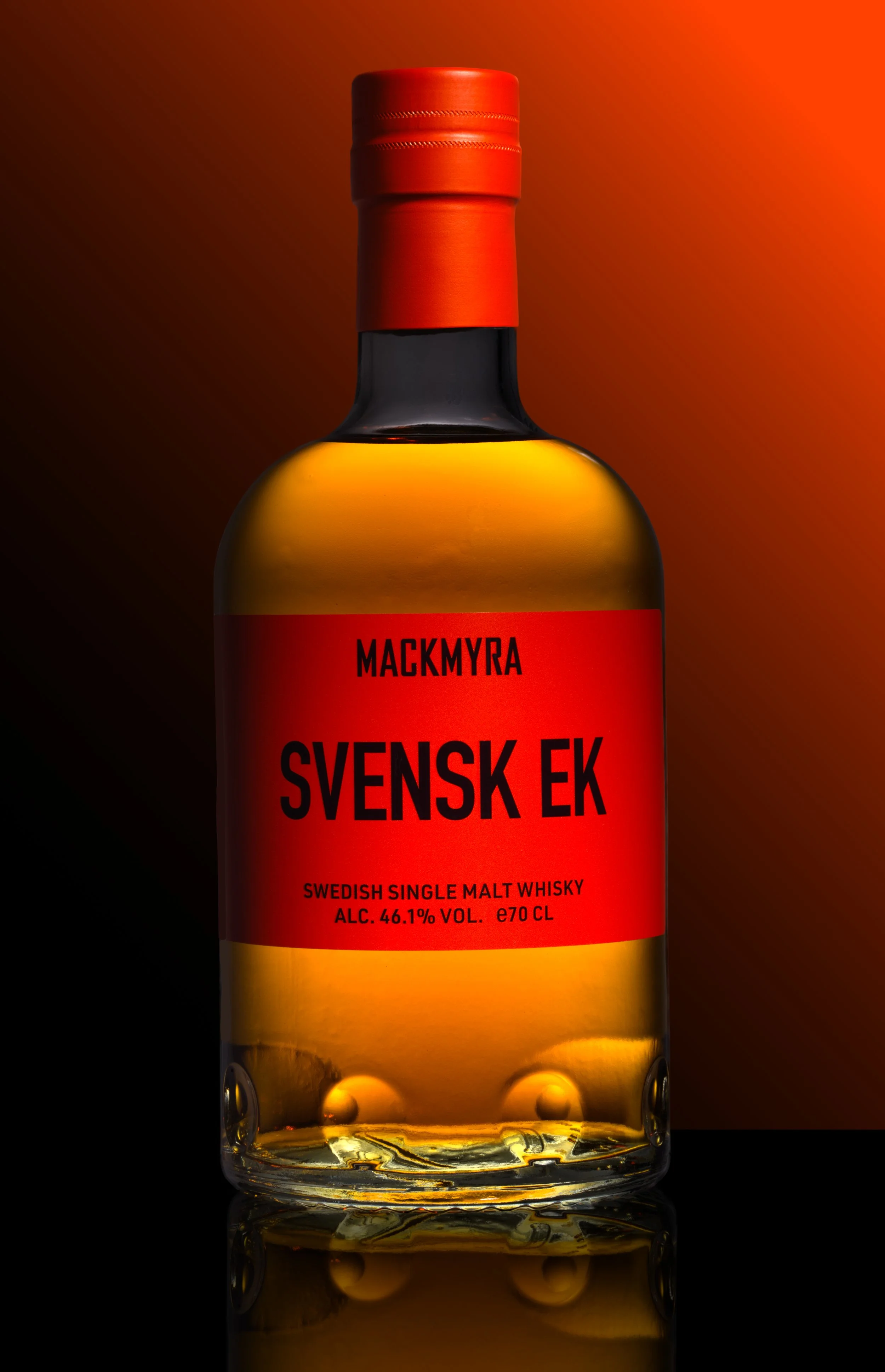 Mackmyra Svensk Ek whisky fotograferad mot en orange bakgrund. Lowkey bild med både ljus och skuggor.