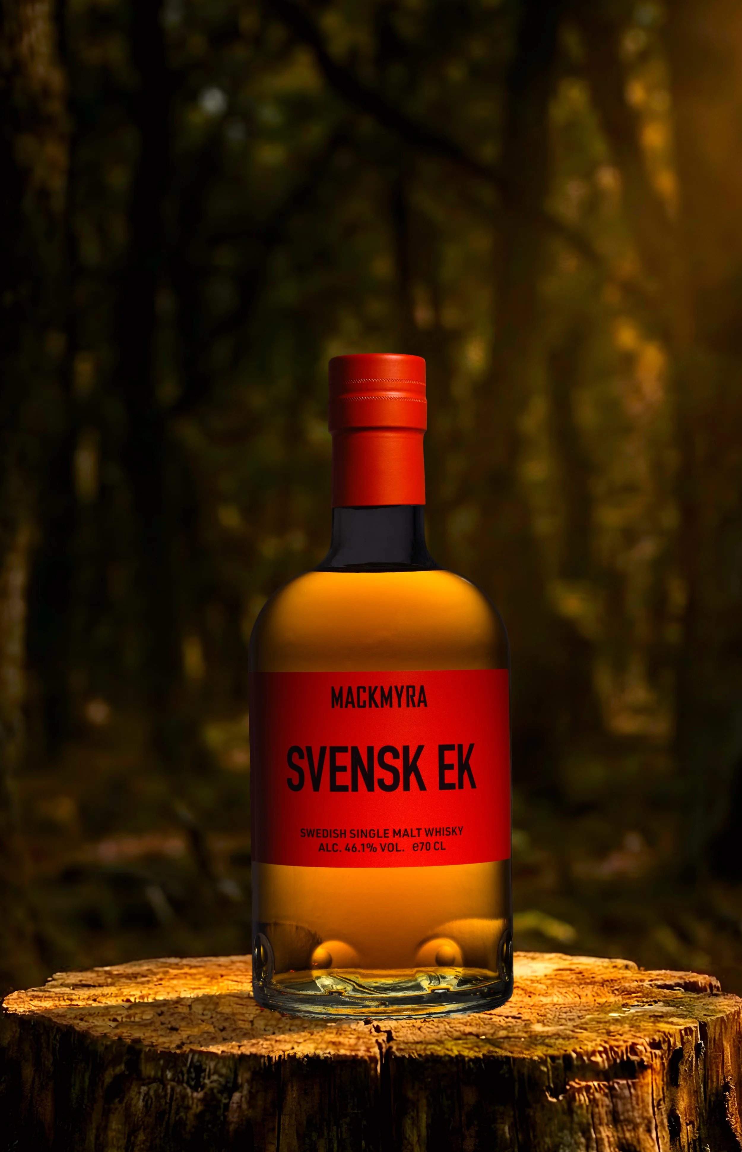 Mackmyra Svensk Ek whisky på en upplyst stubbe i skogen.