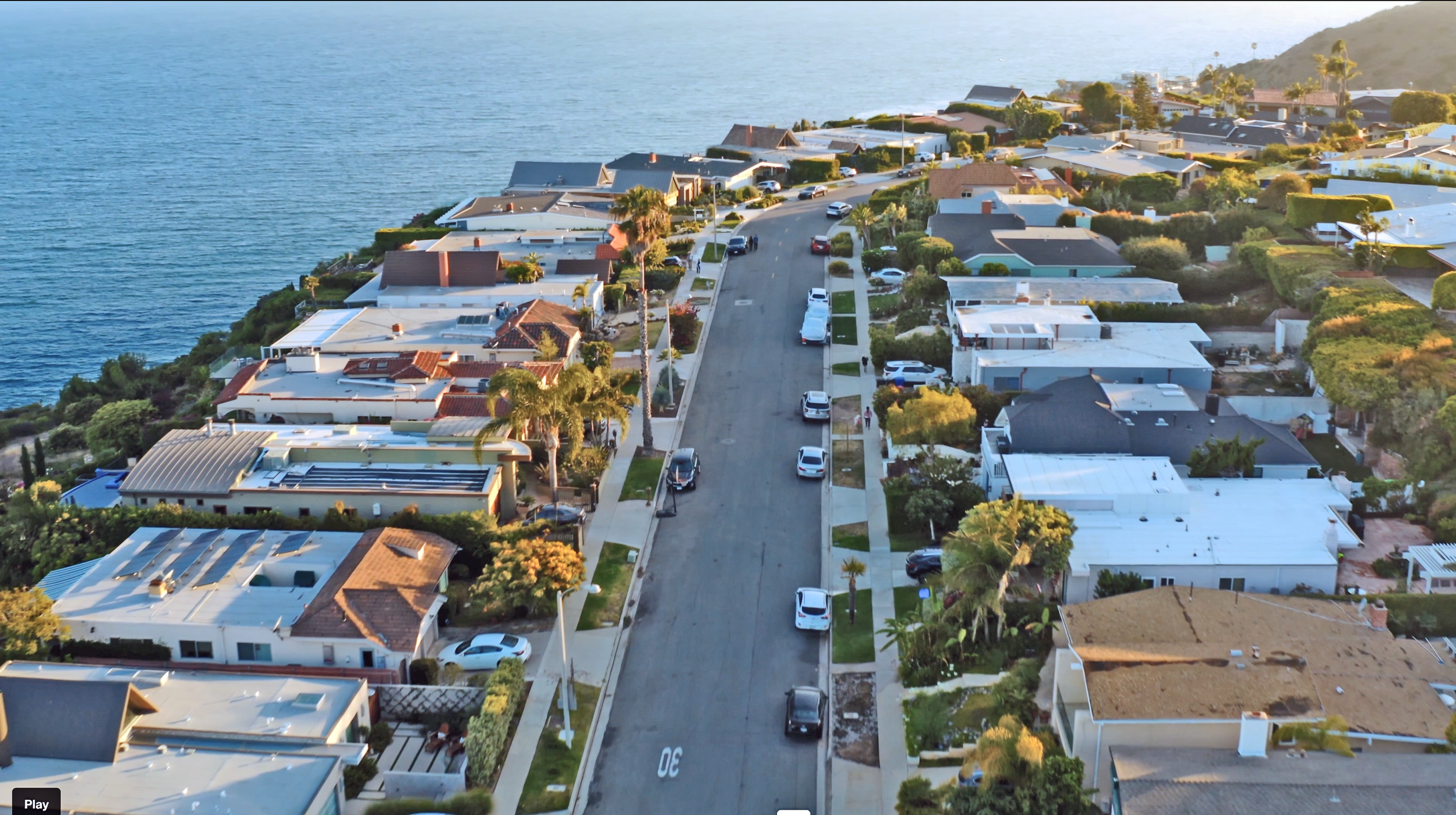 An aerial view of Sunset Mesa with houses along a residential street, overlooking the ocean in the background.
