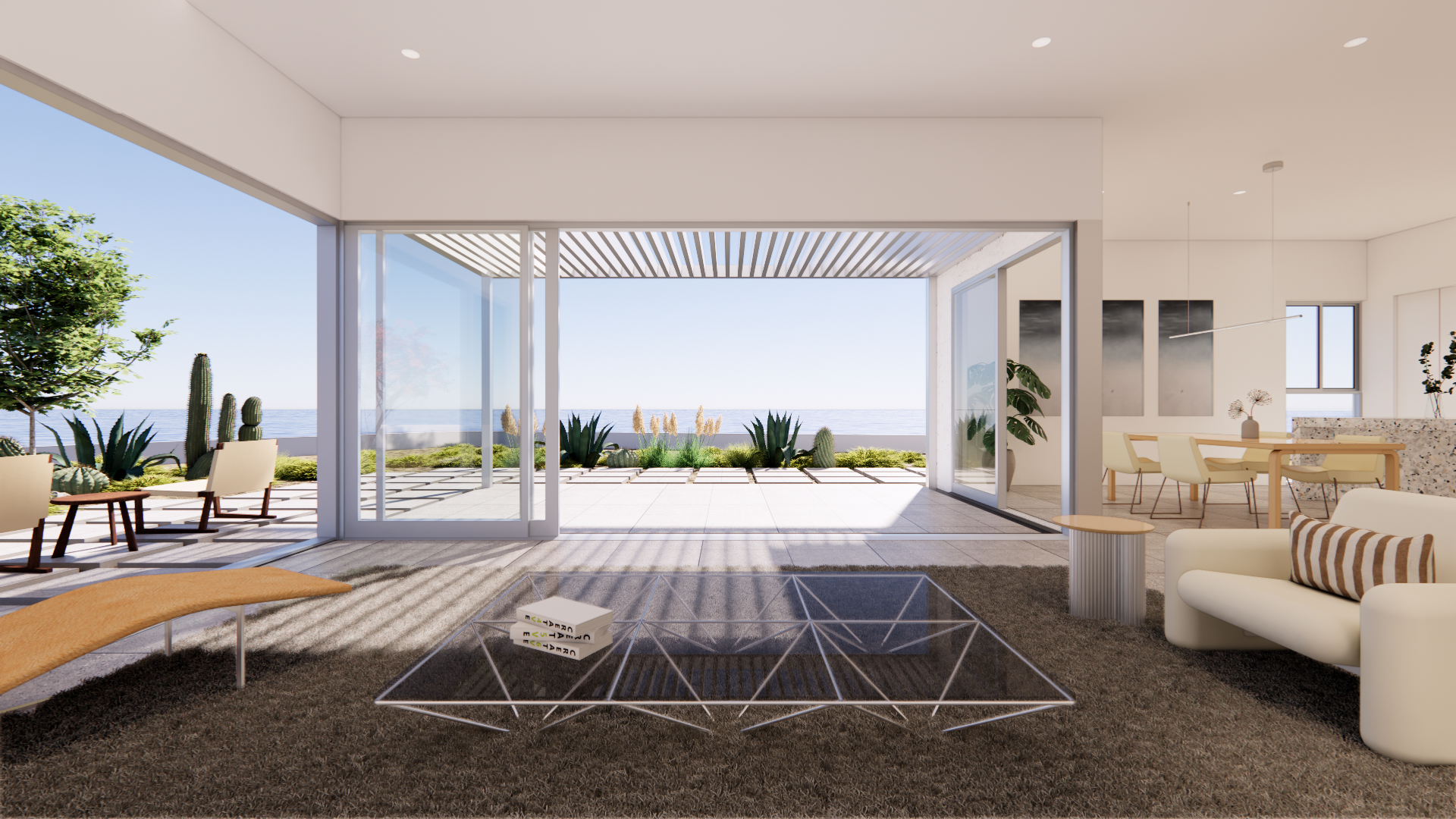 Modern living room with large glass doors opening to a patio and ocean view, furnished with a white sofa with striped pillow, glass coffee table, lounge chairs outside, and a dining table with chairs inside.
