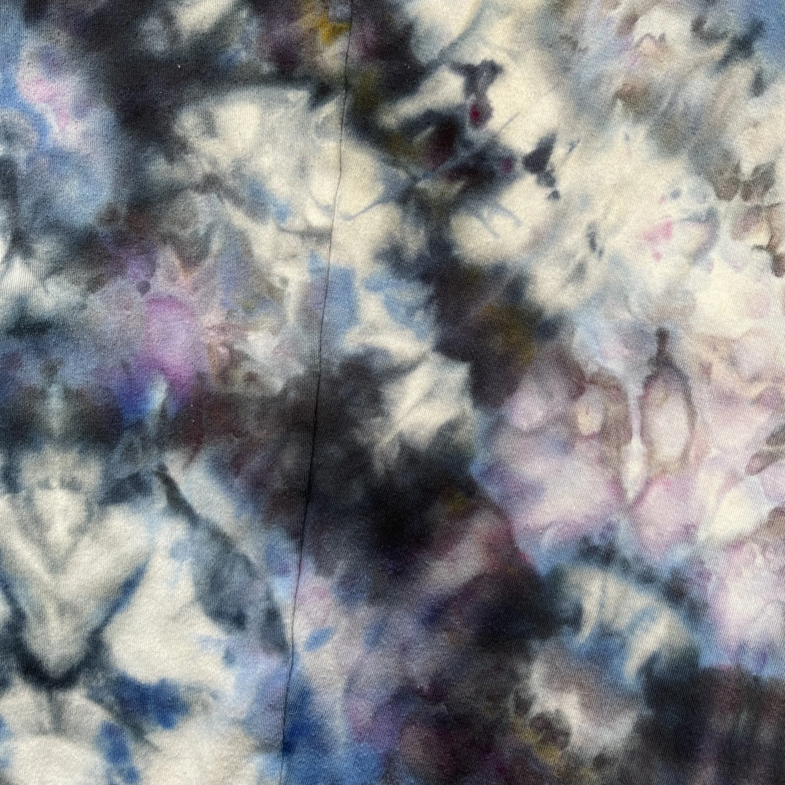 Abstract tie-dye fabric with swirling patterns in shades of black, gray, pink, blue, purple, and white.