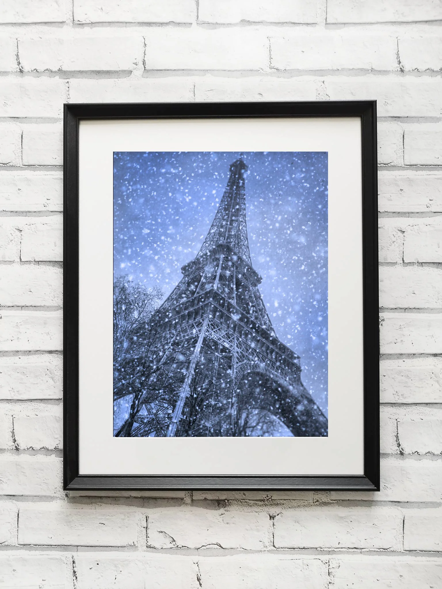 Photograph of the Eiffel Tower covered in snow, taken from a low angle during a snowfall.