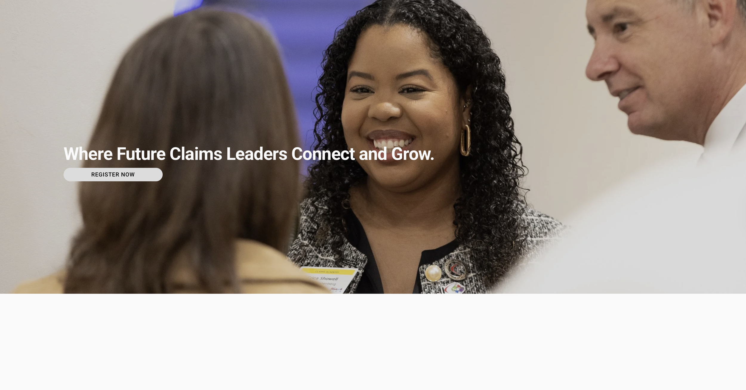 A woman with curly hair and earrings smiling and talking to two people in a professional setting, with a large sign in the background that reads "Where Future Claims Leaders Connect and Grow."