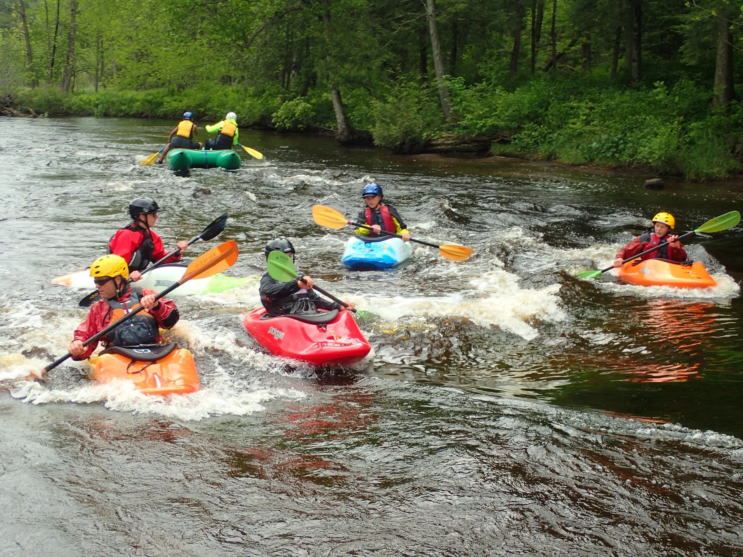 students in small kayaks going down rapids