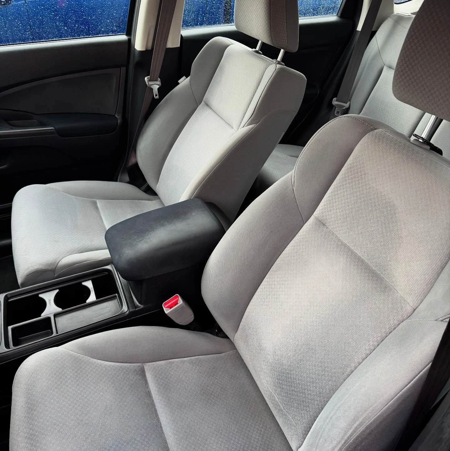 Interior view of a car showing grey fabric front seats, cup holders, and center console.
