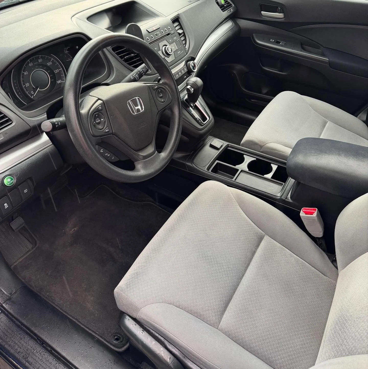 Interior of a Honda vehicle showing the steering wheel, dashboard, gear shift, and front seats with cup holders and center console.