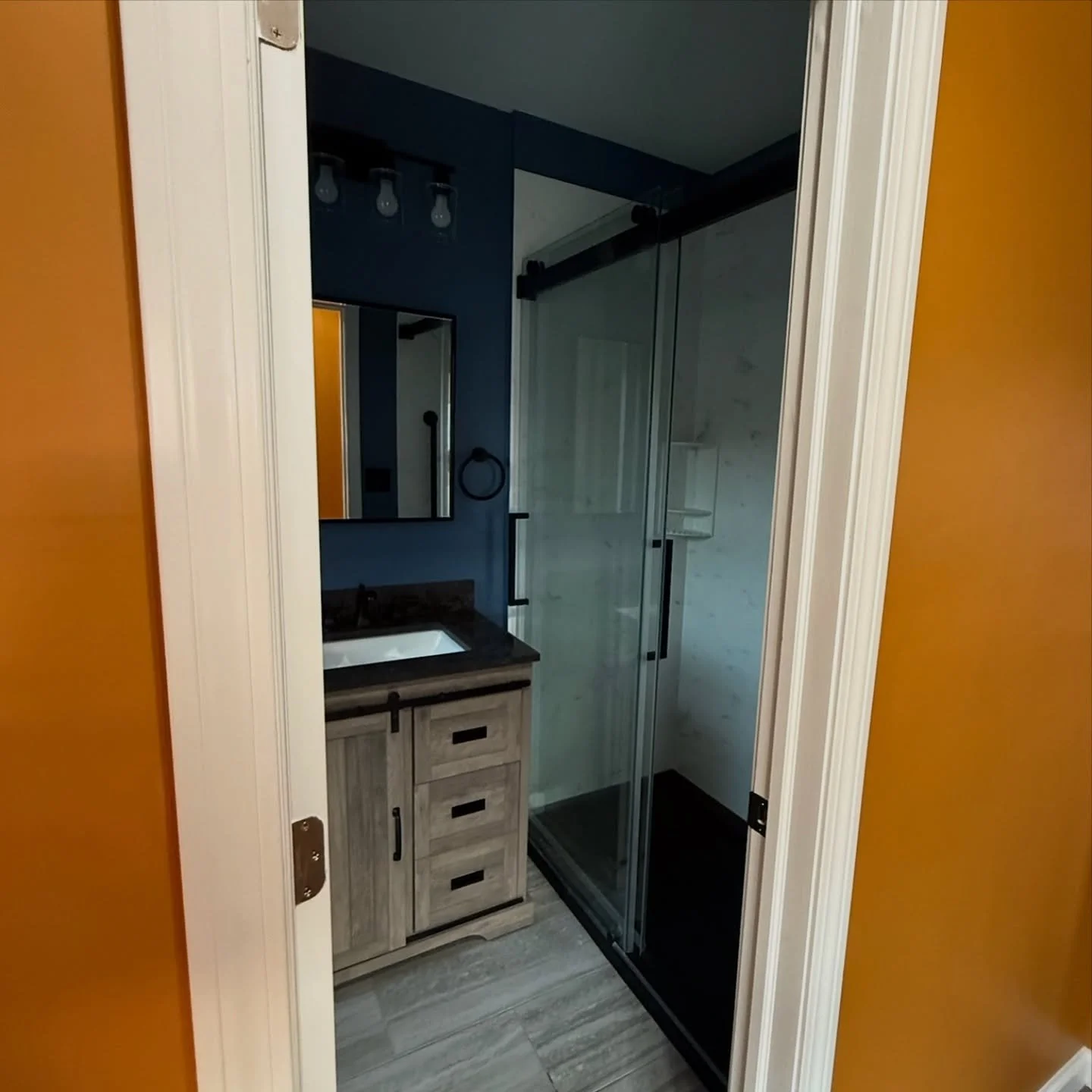 From outdated to outstanding ✨ This remodel brought fresh life to both the bathroom and hallway &mdash; with a custom shower, new vanity, fresh paint, and sleek flooring. The hallway now shines with a new door, ceiling, trim, and a whole new vibe. #H