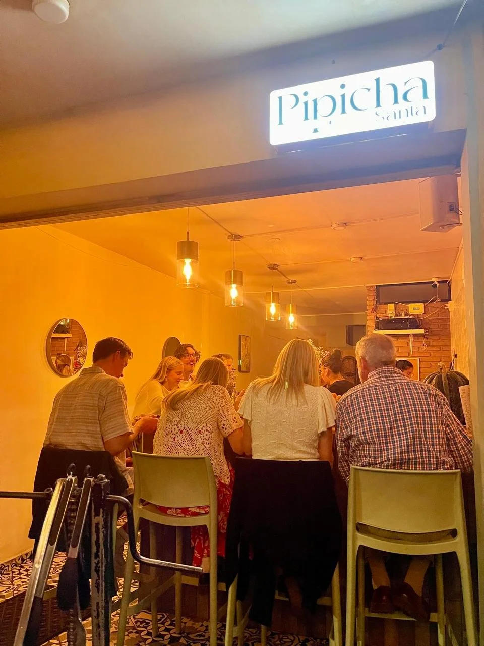 People socializing at a bar or restaurant with warm lighting and modern decor