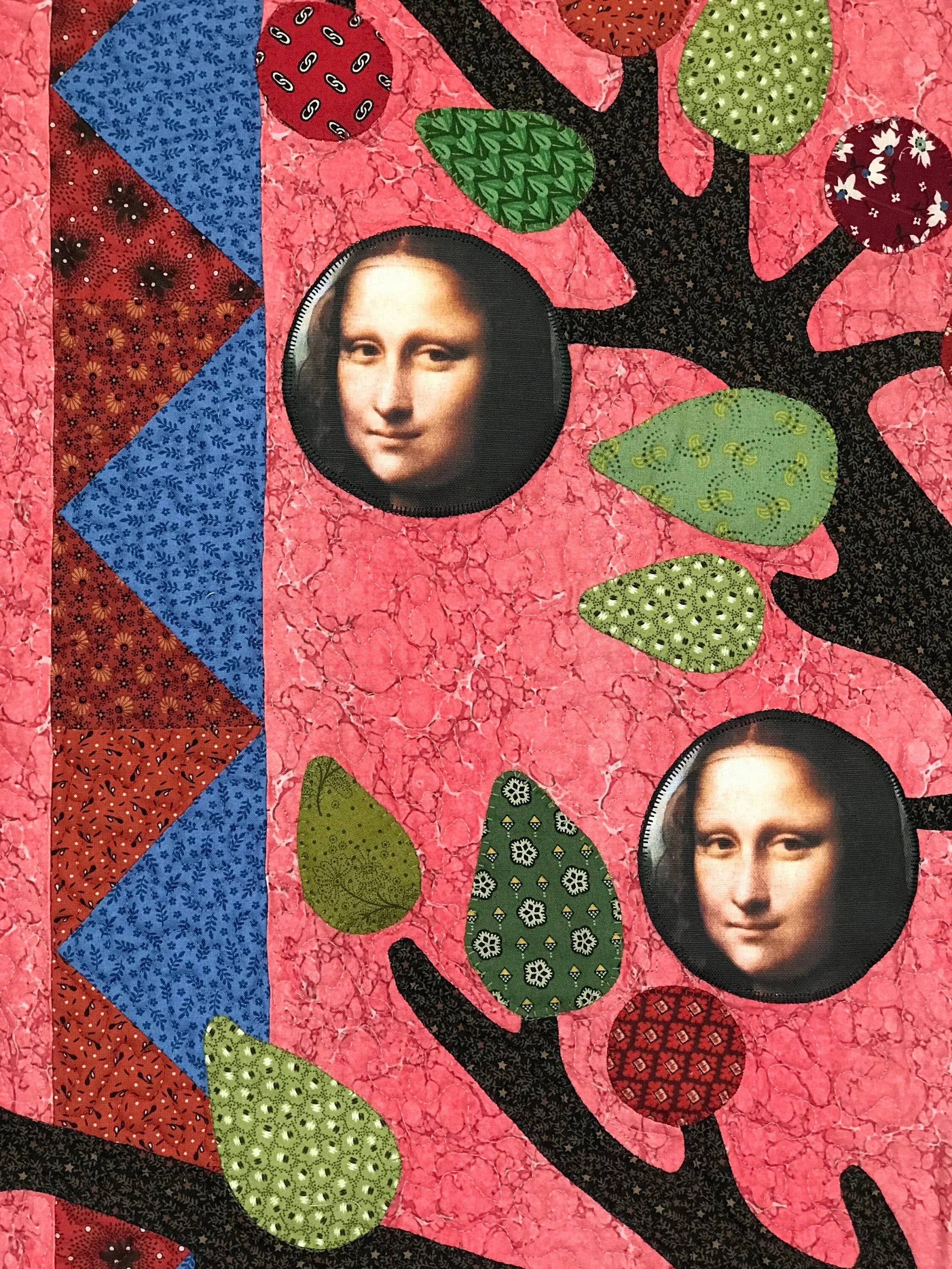 detail of art quilt featuring applique fruit branches and leaves on a pink background