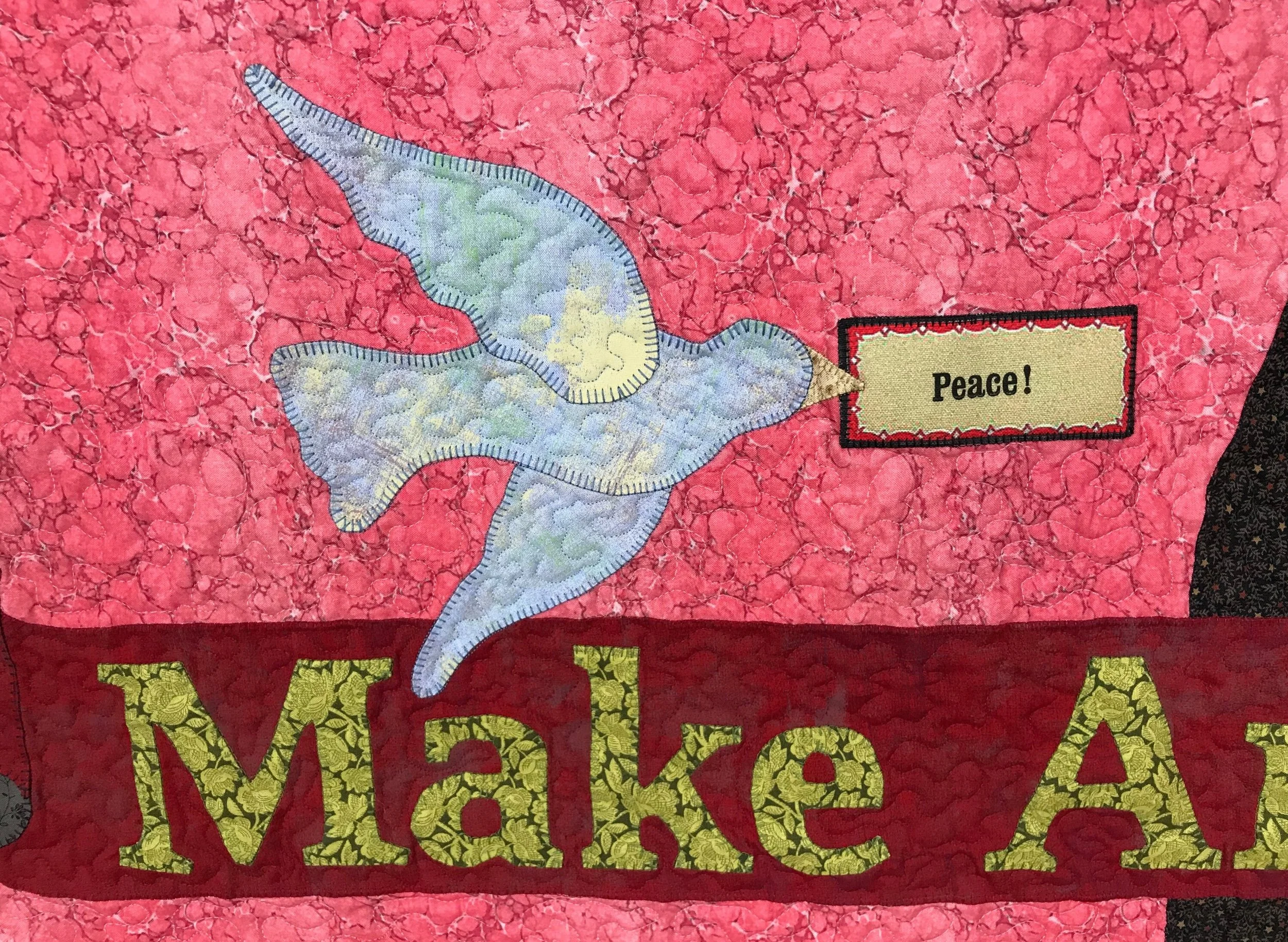 detail of a folk art quilt featuring an appliqued peach dove with a message of love