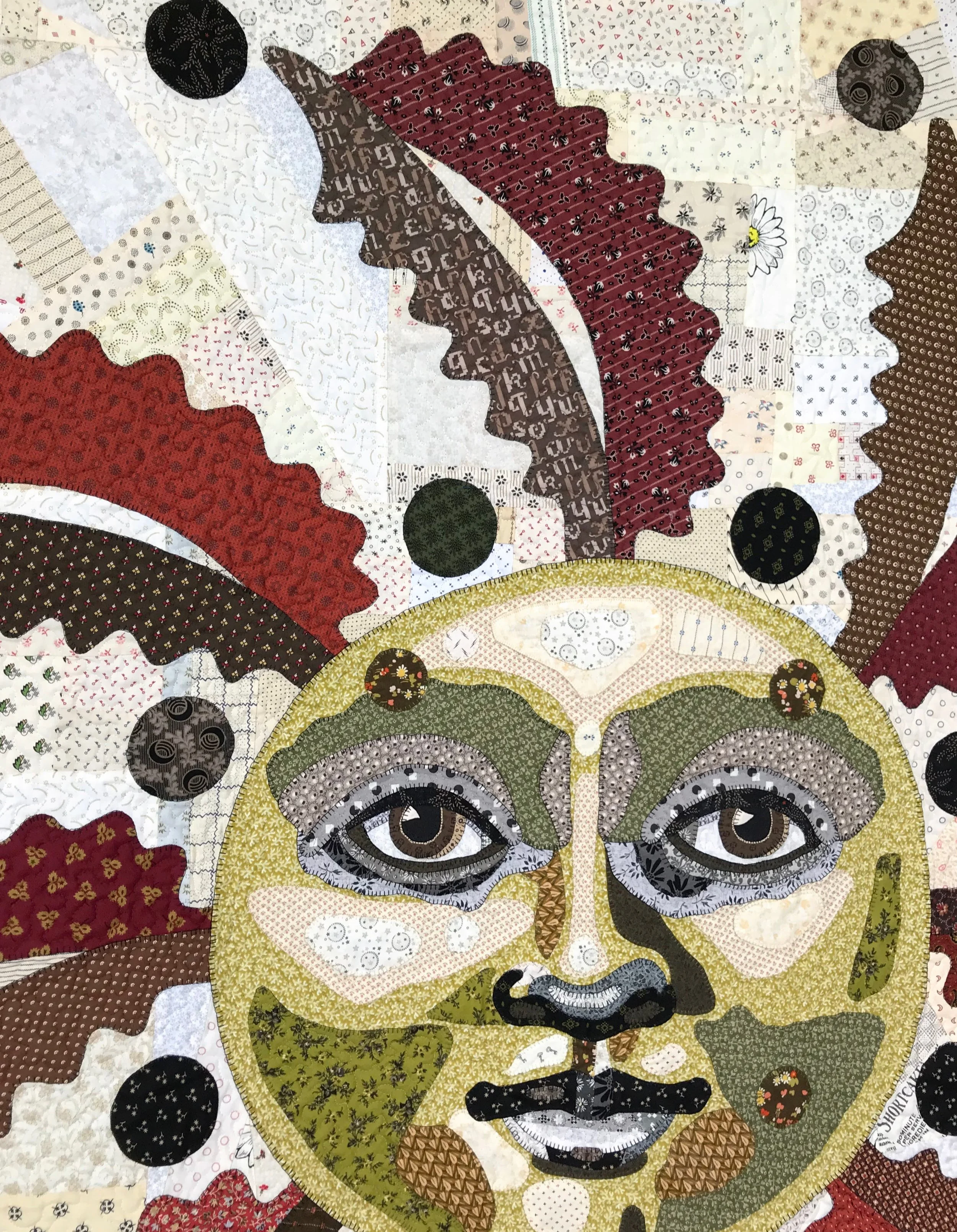fine art quilt detail with red and gold sun