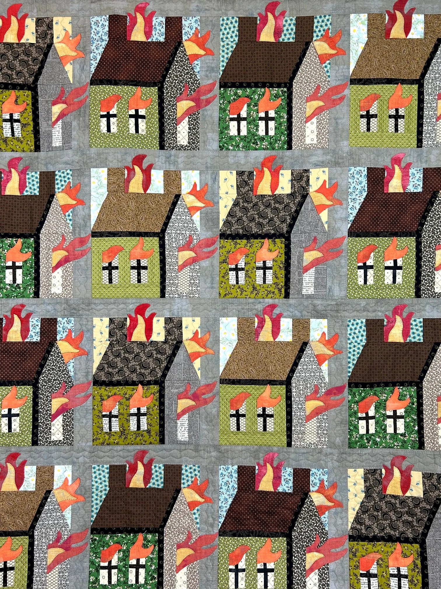 textile folk art quilt depicting burning houses in patchwork