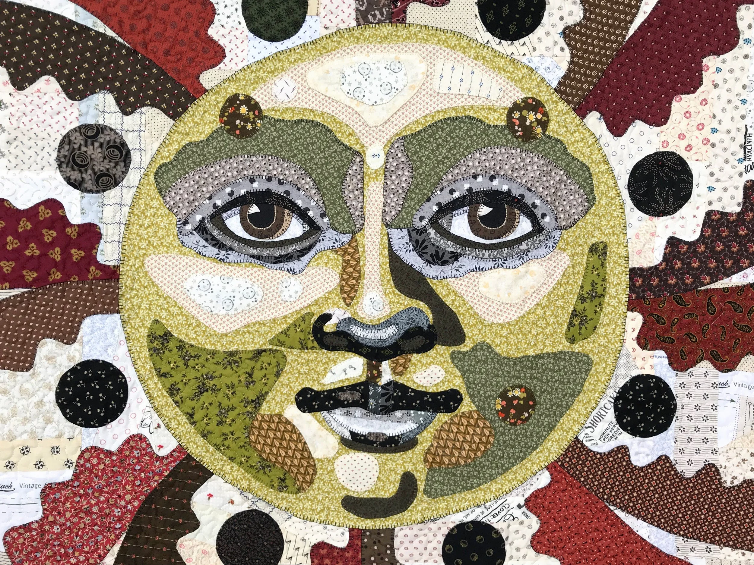 pictorial folk art quilt with face appliqued with a blanket stitch